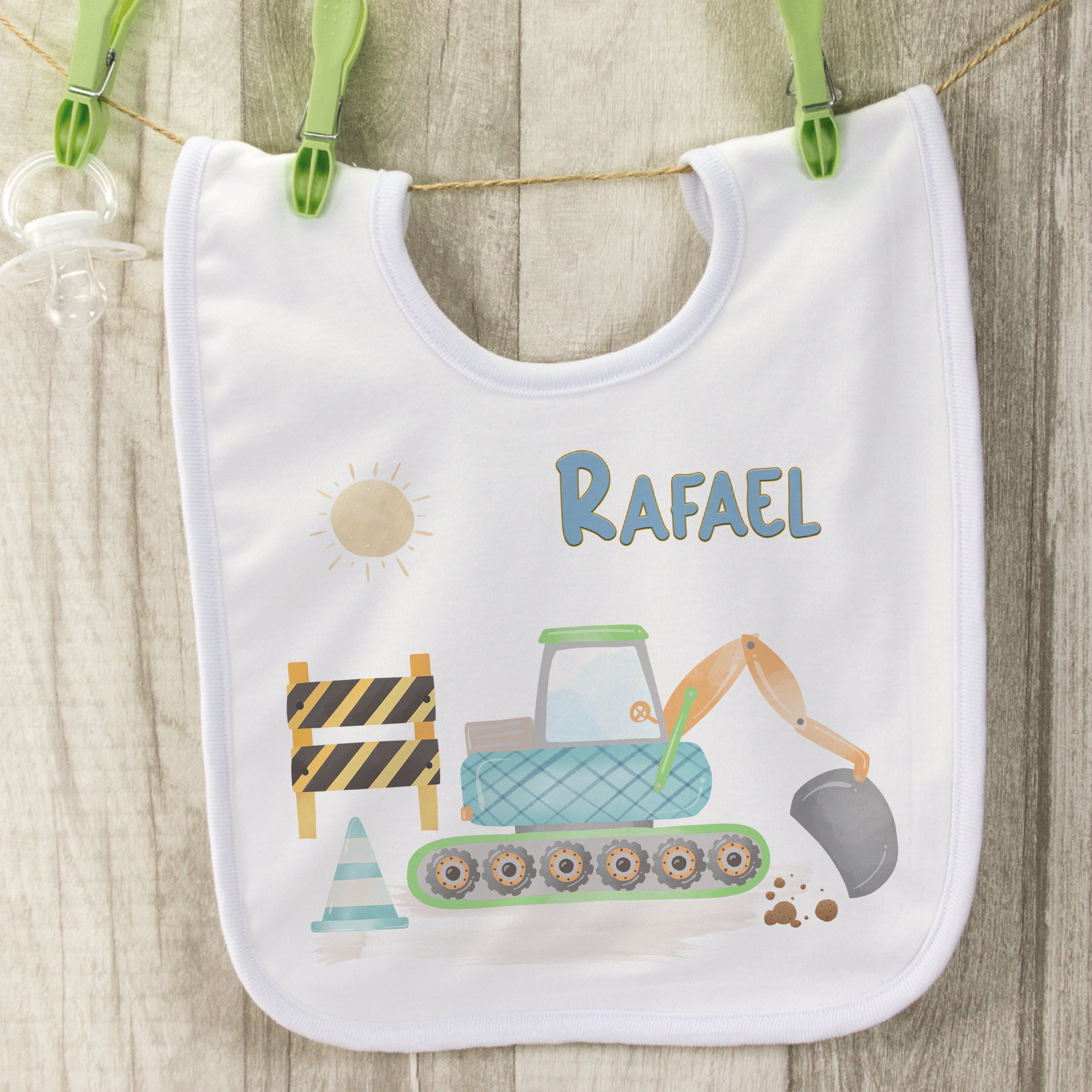 Weißes Lätzchen mit Bagger-Motiv und dem Namen Rafael.