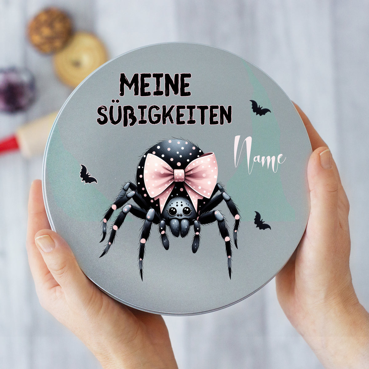 Graue Dose mit Spinne und rosa Schleife, personalisierbar.