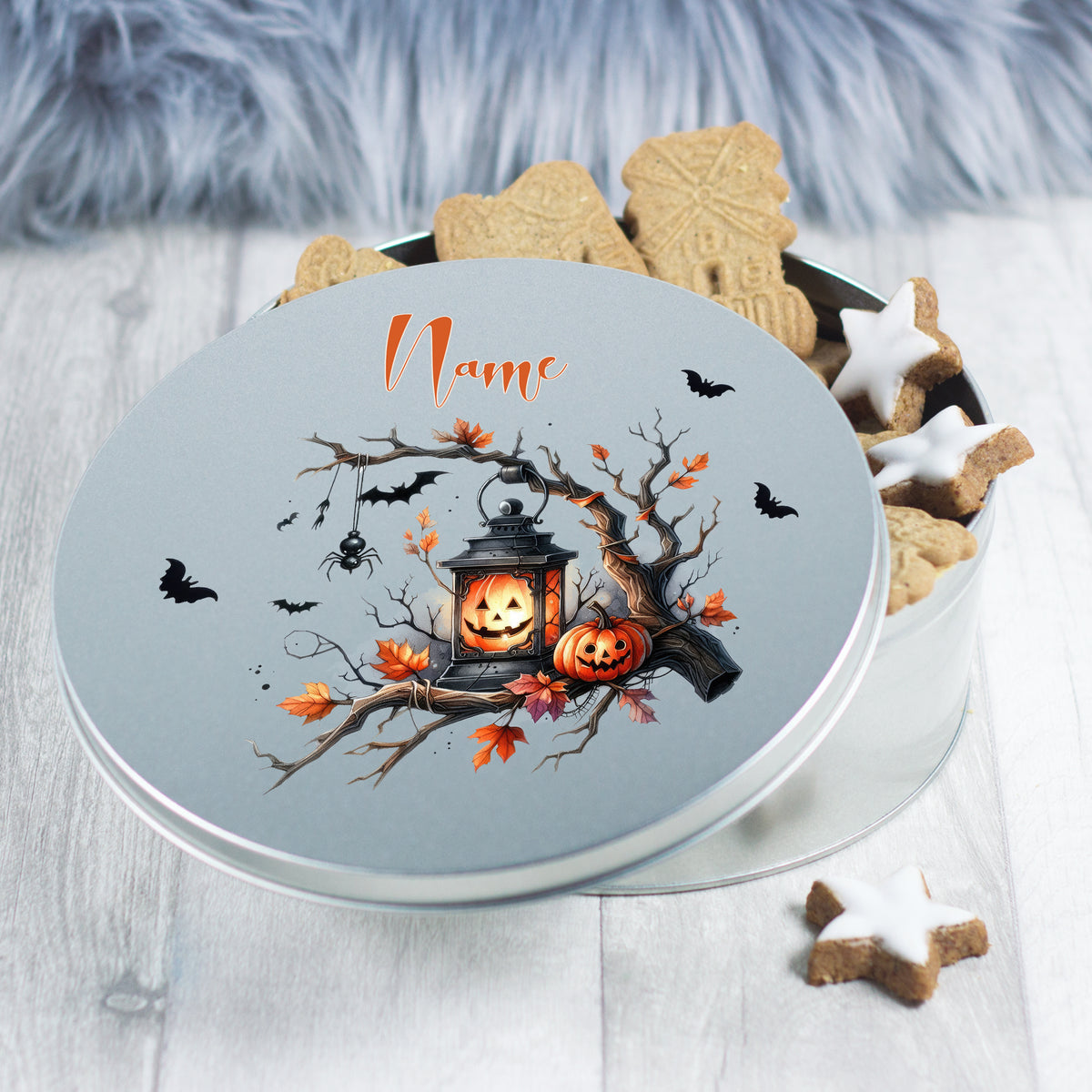 Runde Blechdose mit Halloween-Motiv, orangefarbene Kürbisse und Fledermäuse.
