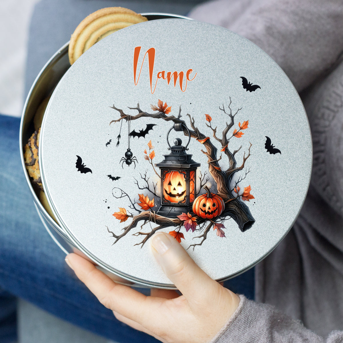 Graue Keksdose mit Halloween-Motiv, Kürbis und Laterne.