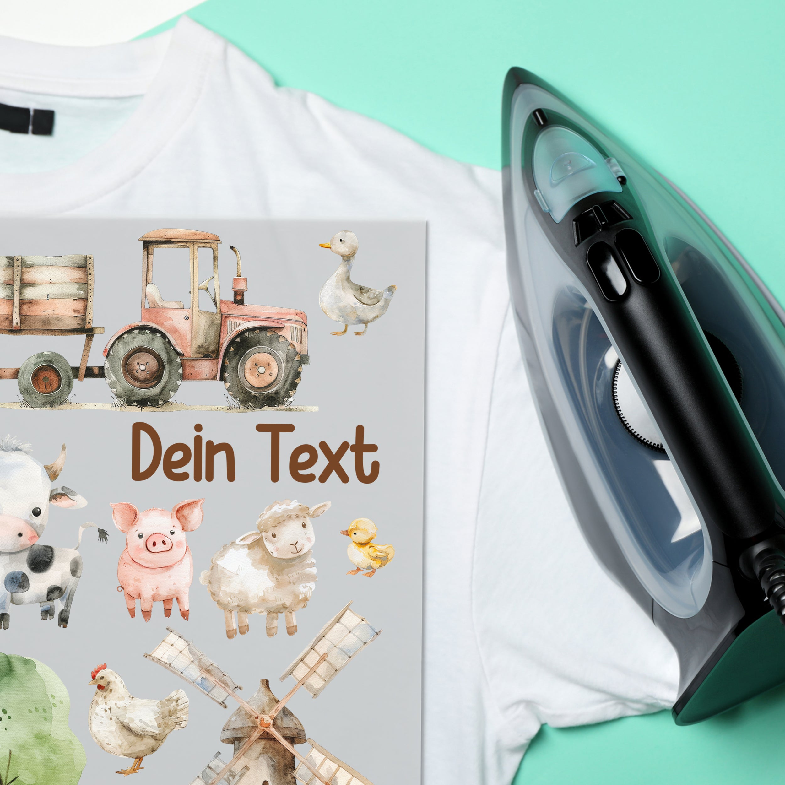 Weißes T-Shirt mit buntem Bauernhof-Motiv und Bügeleisen.