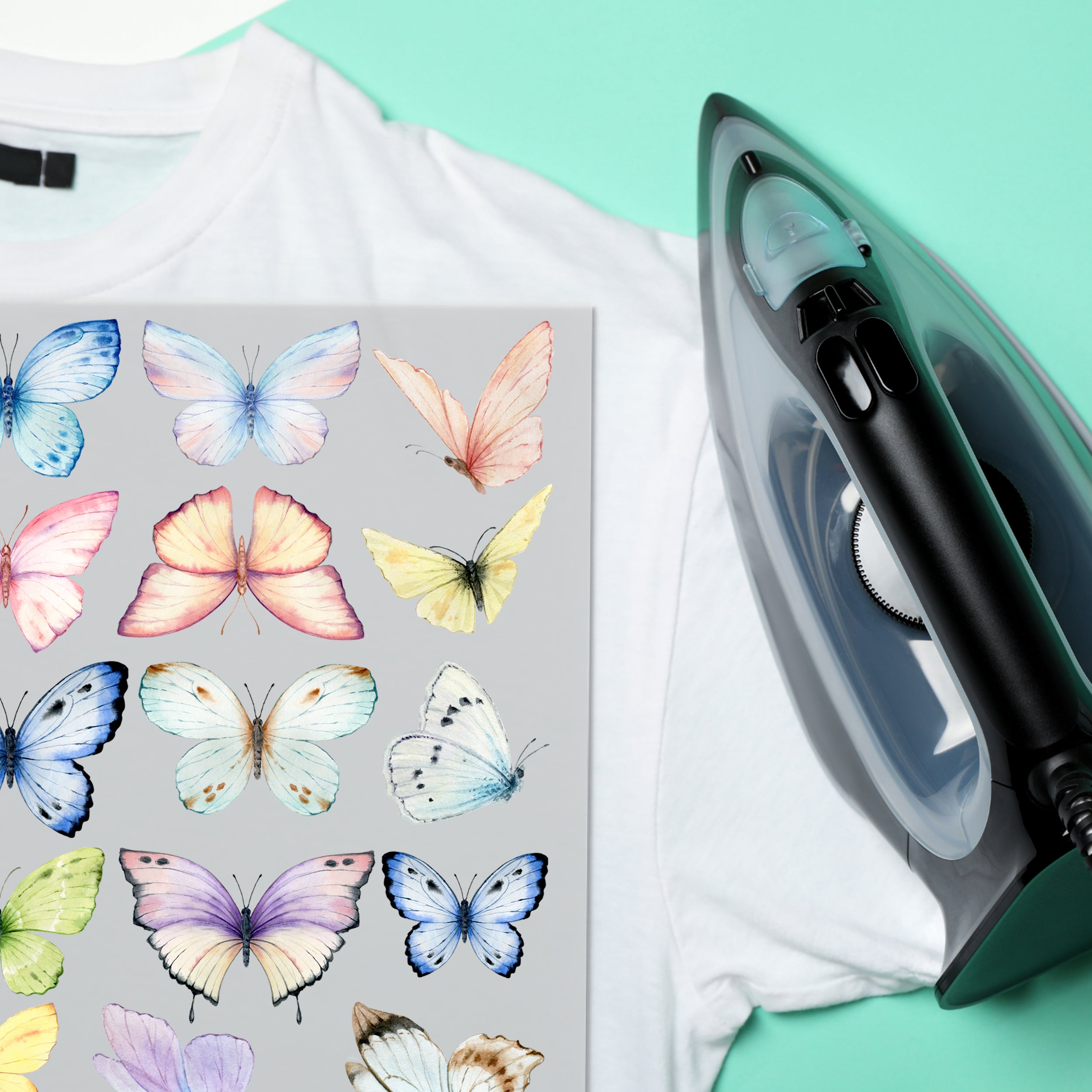 Weißes T-Shirt mit bunten Schmetterlingen und Dampfbügeleisen.