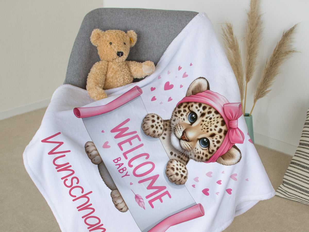 Babydecke mit Leopardenmotiv, rosa Akzenten und Willkommensschrift.