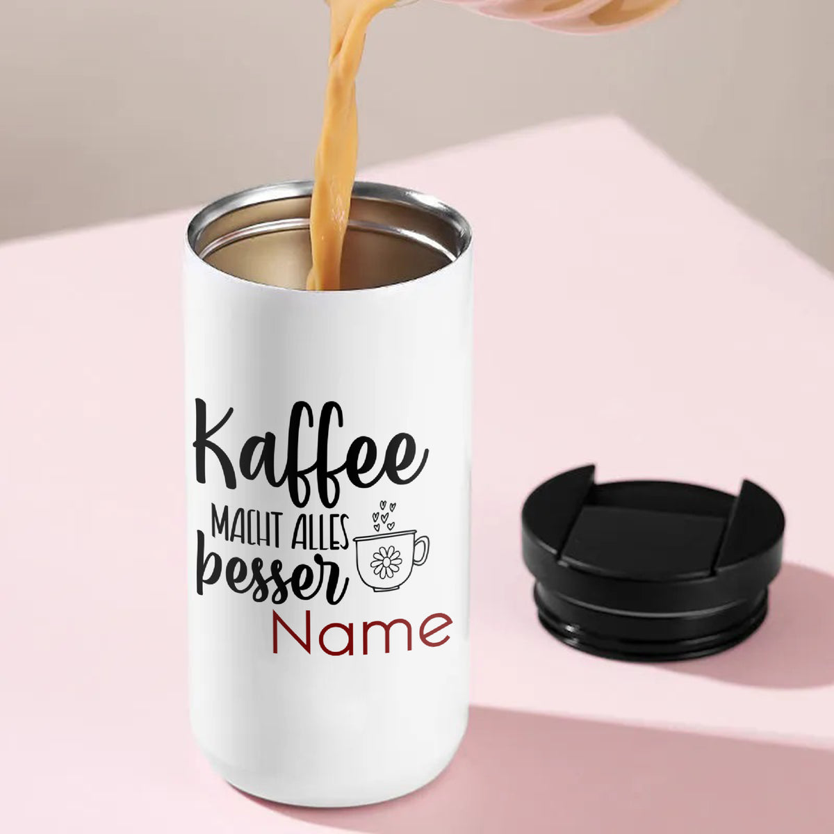 Weißer Kaffeebecher mit Aufschrift und schwarzem Deckel.