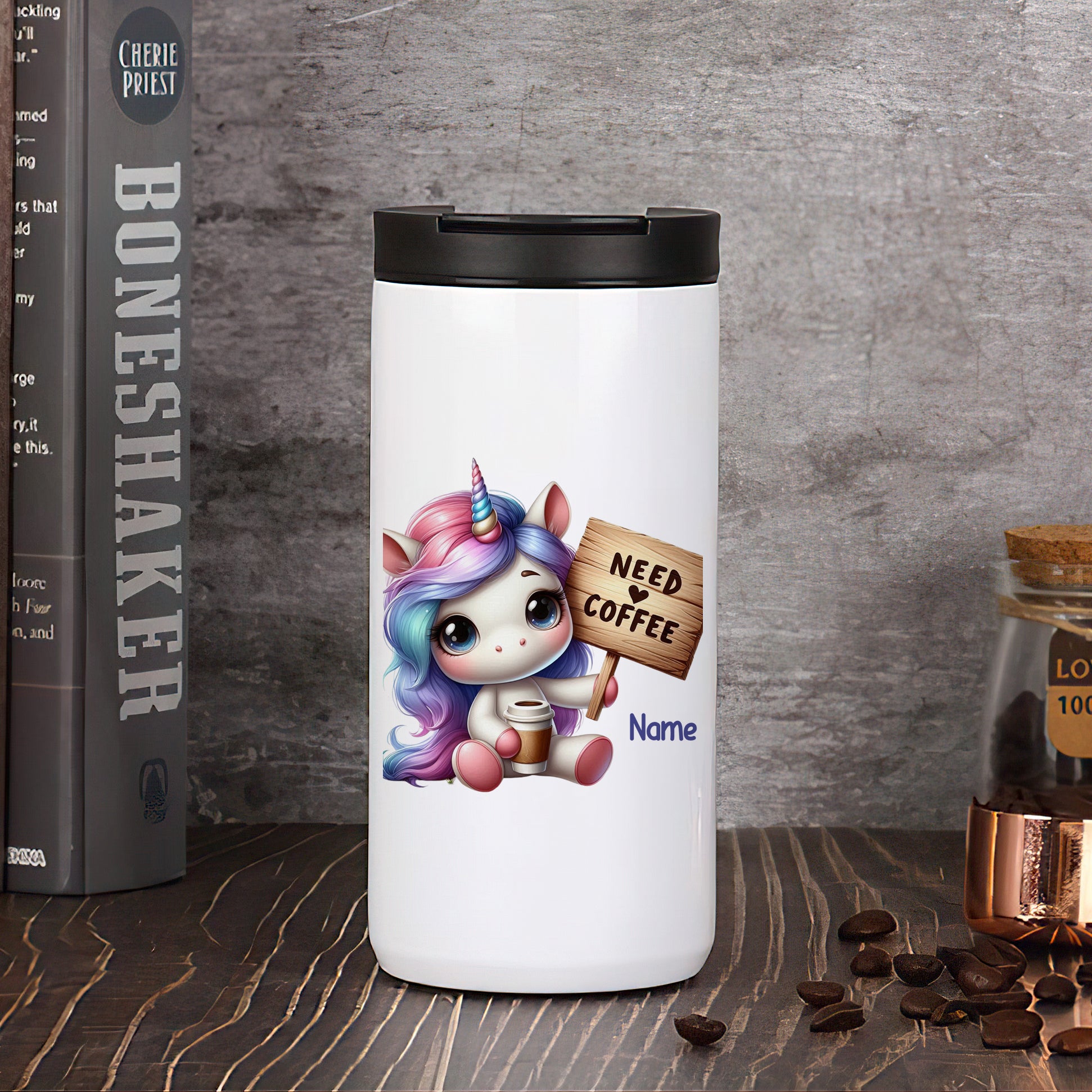 Weißer Kaffeebecher mit Einhorn und "Need Coffee"-Schild.