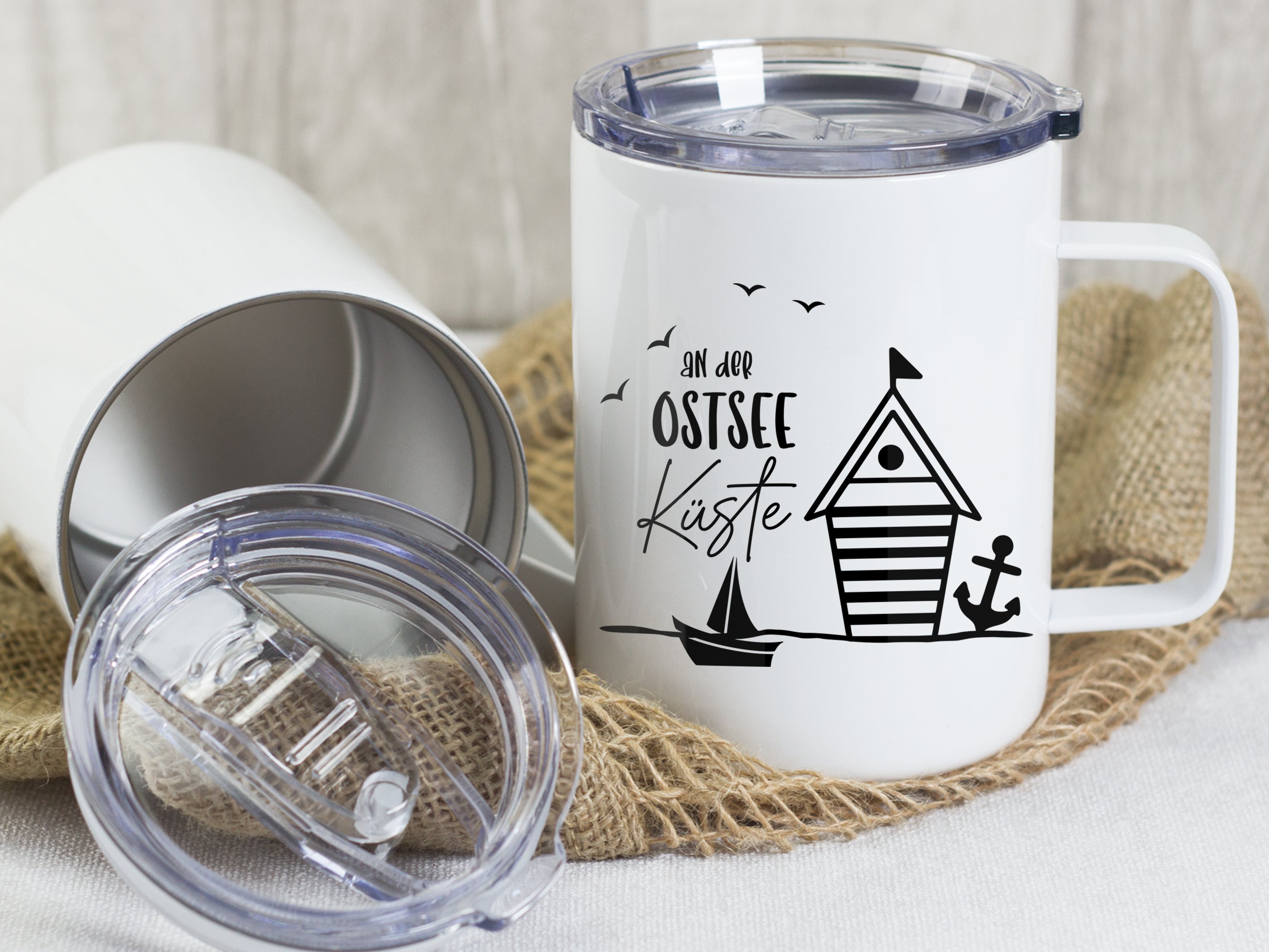 Weißer Becher mit Ostsee-Motiv, Schiff und Strandhaus.
