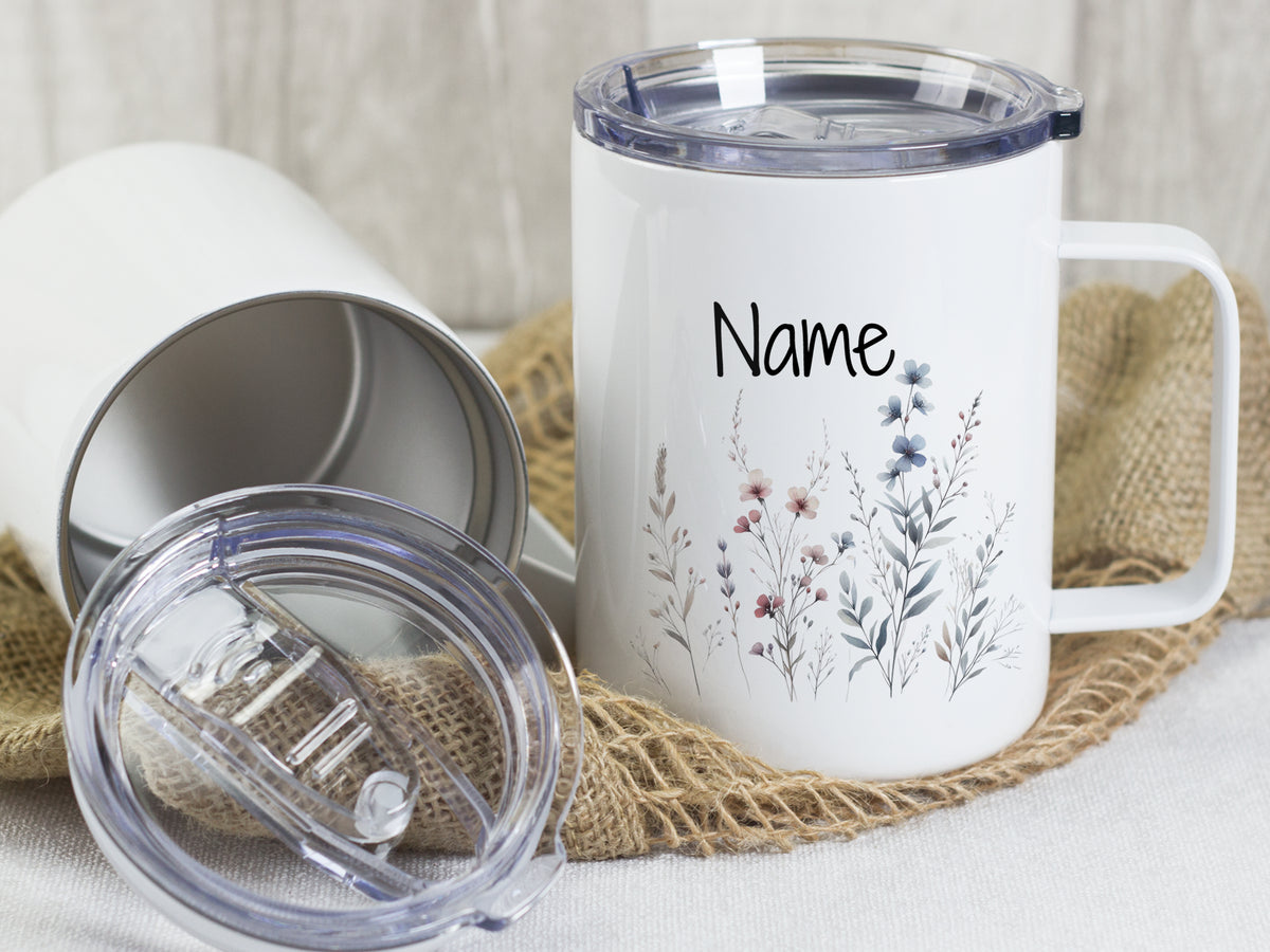 Weißer Becher mit floralen Motiven und personalisiertem Namen.