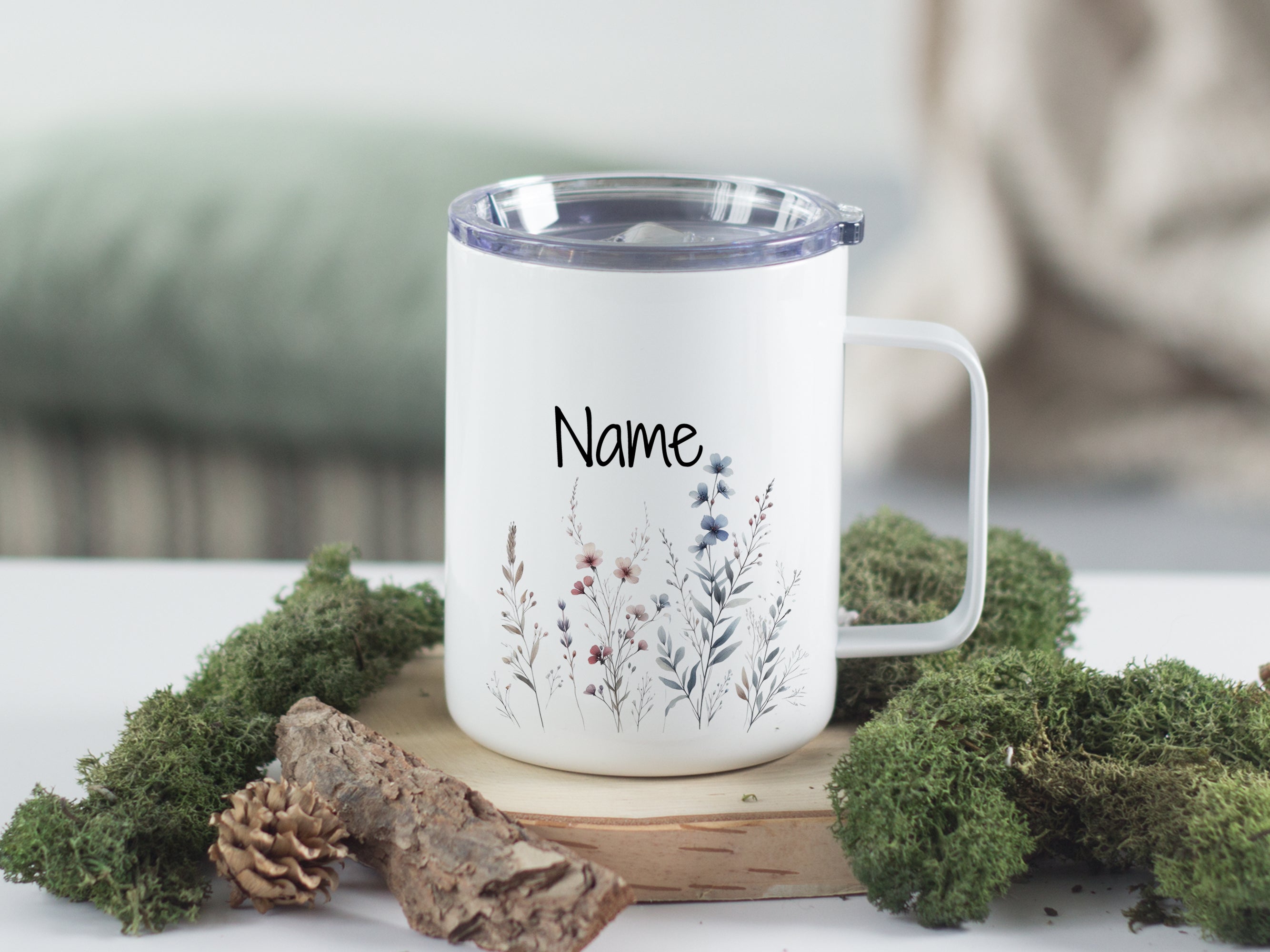 Weißer Becher mit floralen Motiven und personalisiertem Namen.