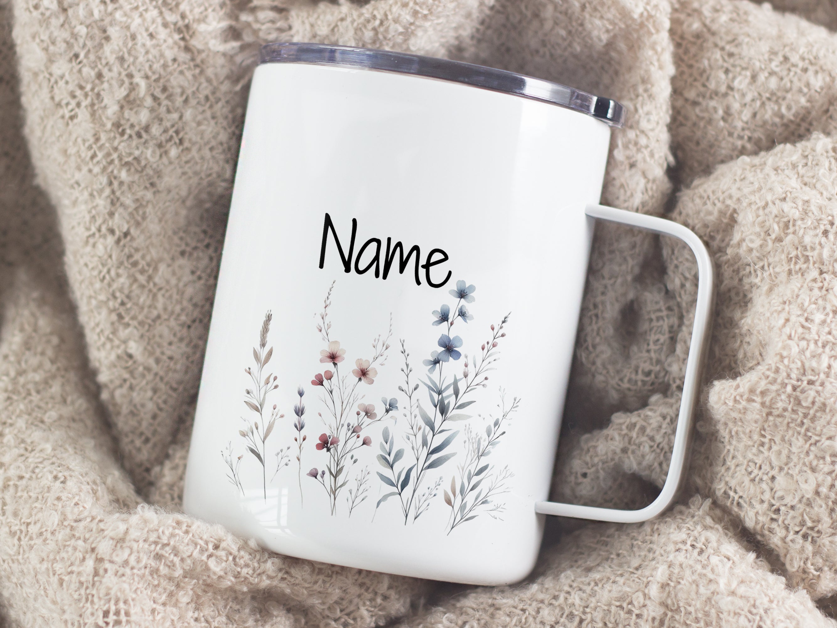 Weiße Tasse mit floralen Motiven und personalisiertem Namen.