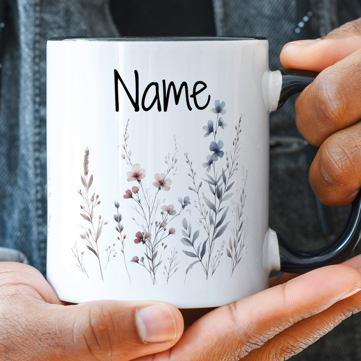 Weißer Becher mit floralen Motiven und personalisiertem Namen.