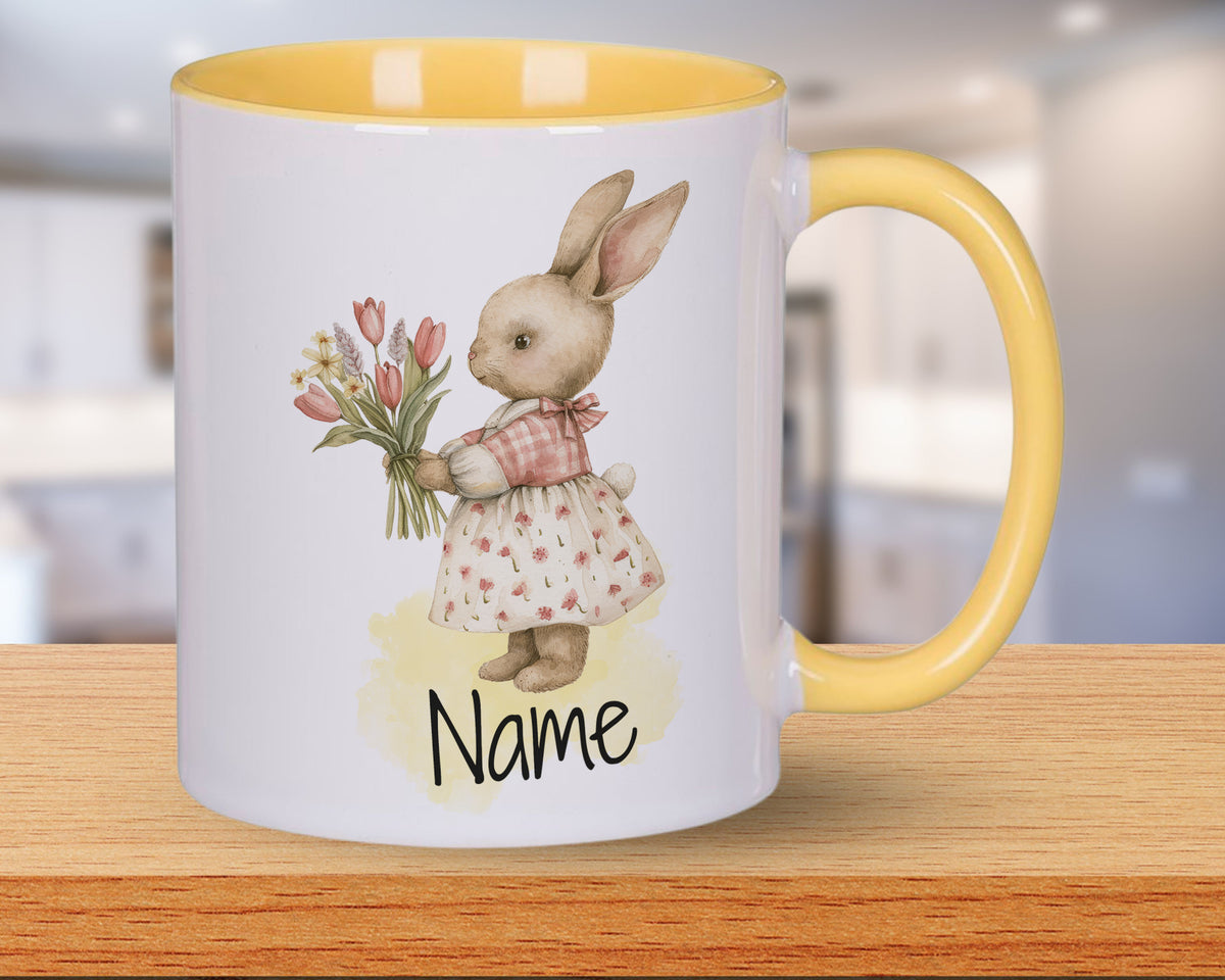 Tasse mit gelbem Henkel, Kaninchen und Blumenmotiv.