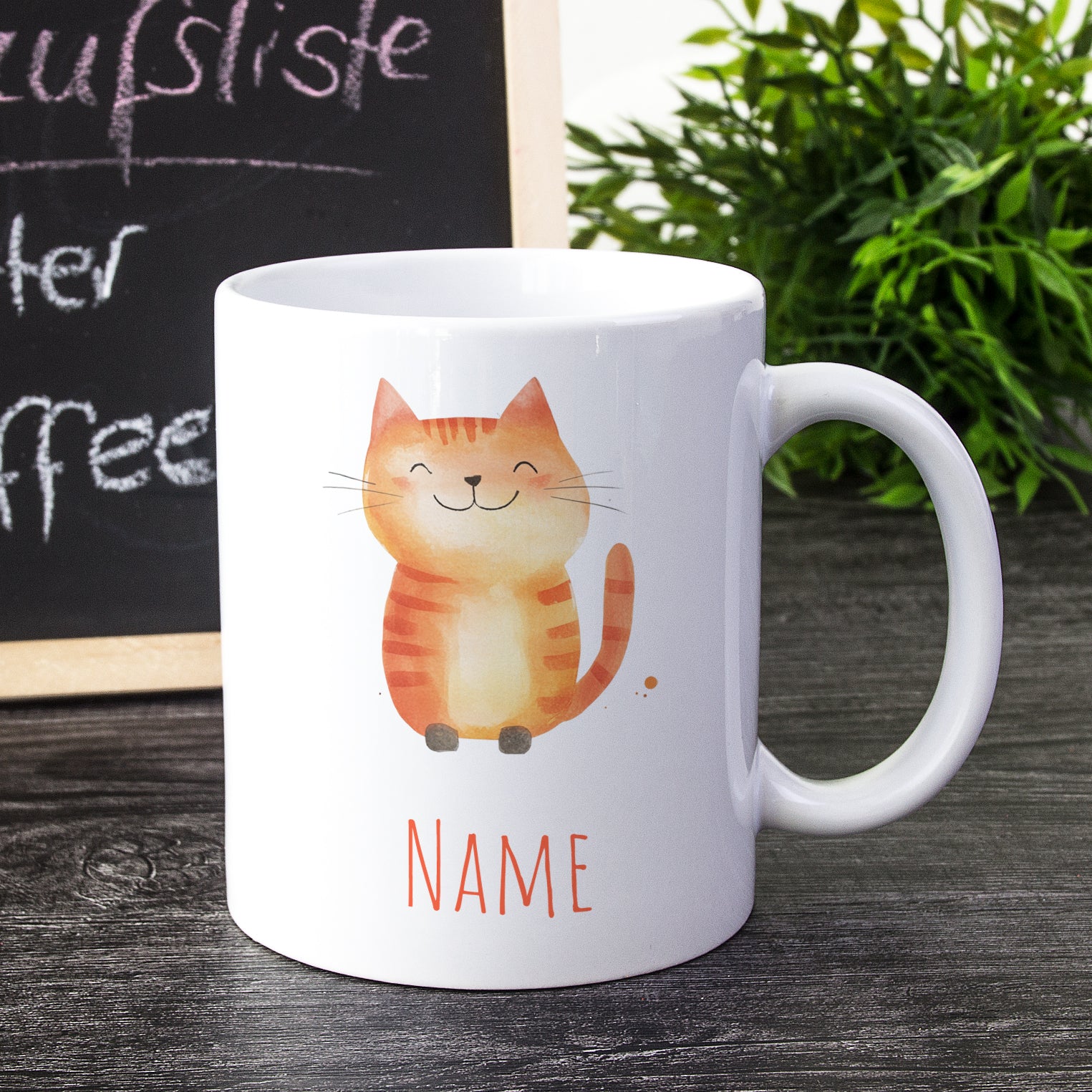 Weiße Tasse mit lächelnder orangefarbener Katze und Name.