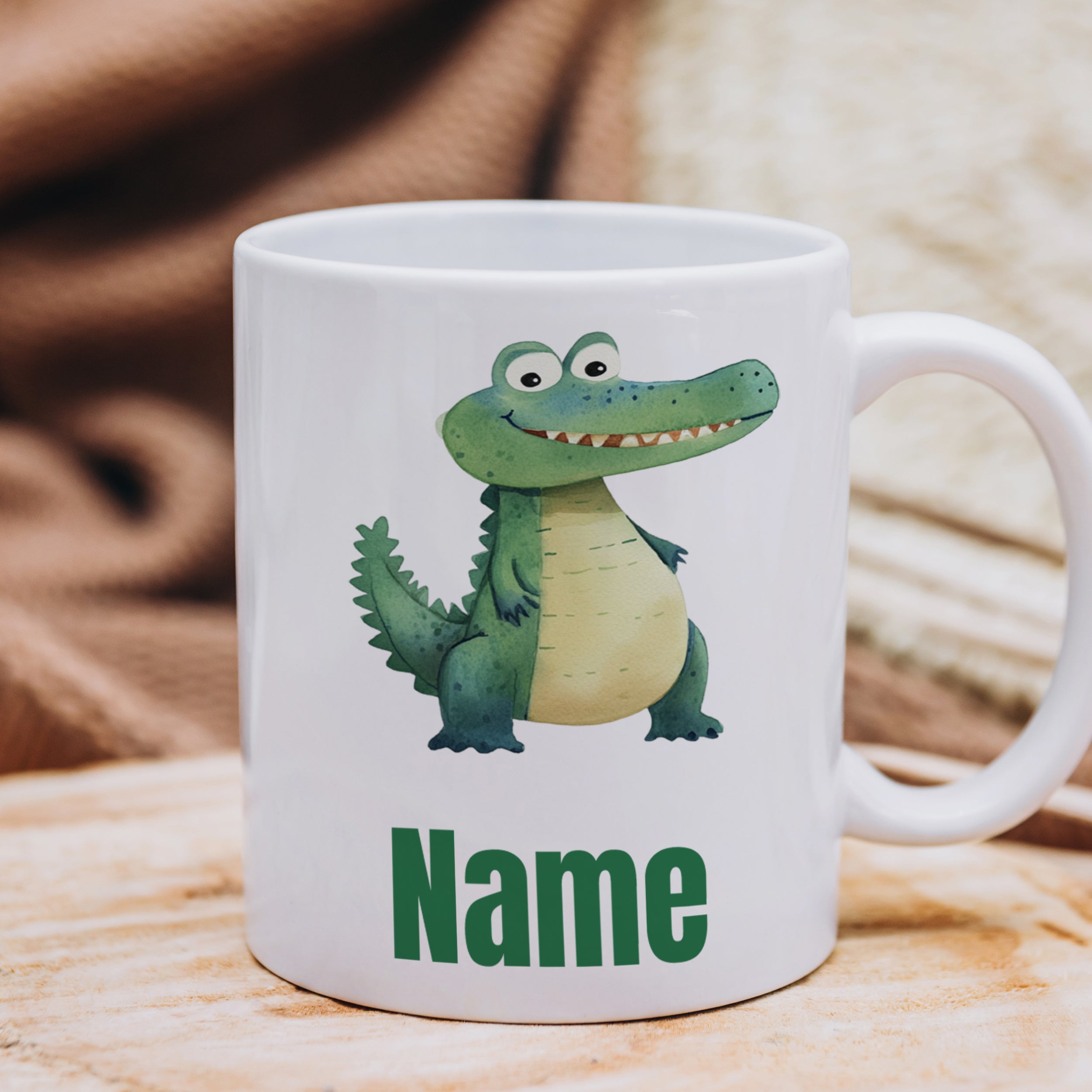 Weißer Becher mit Krokodil-Motiv und grünem Text „Name“.