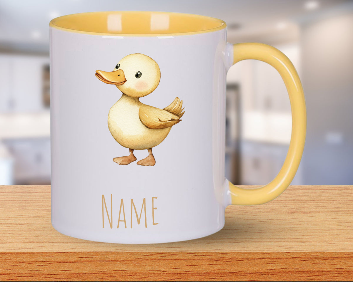 Gelbe Tasse mit Entenmotiv und personalisierbarem Namen.