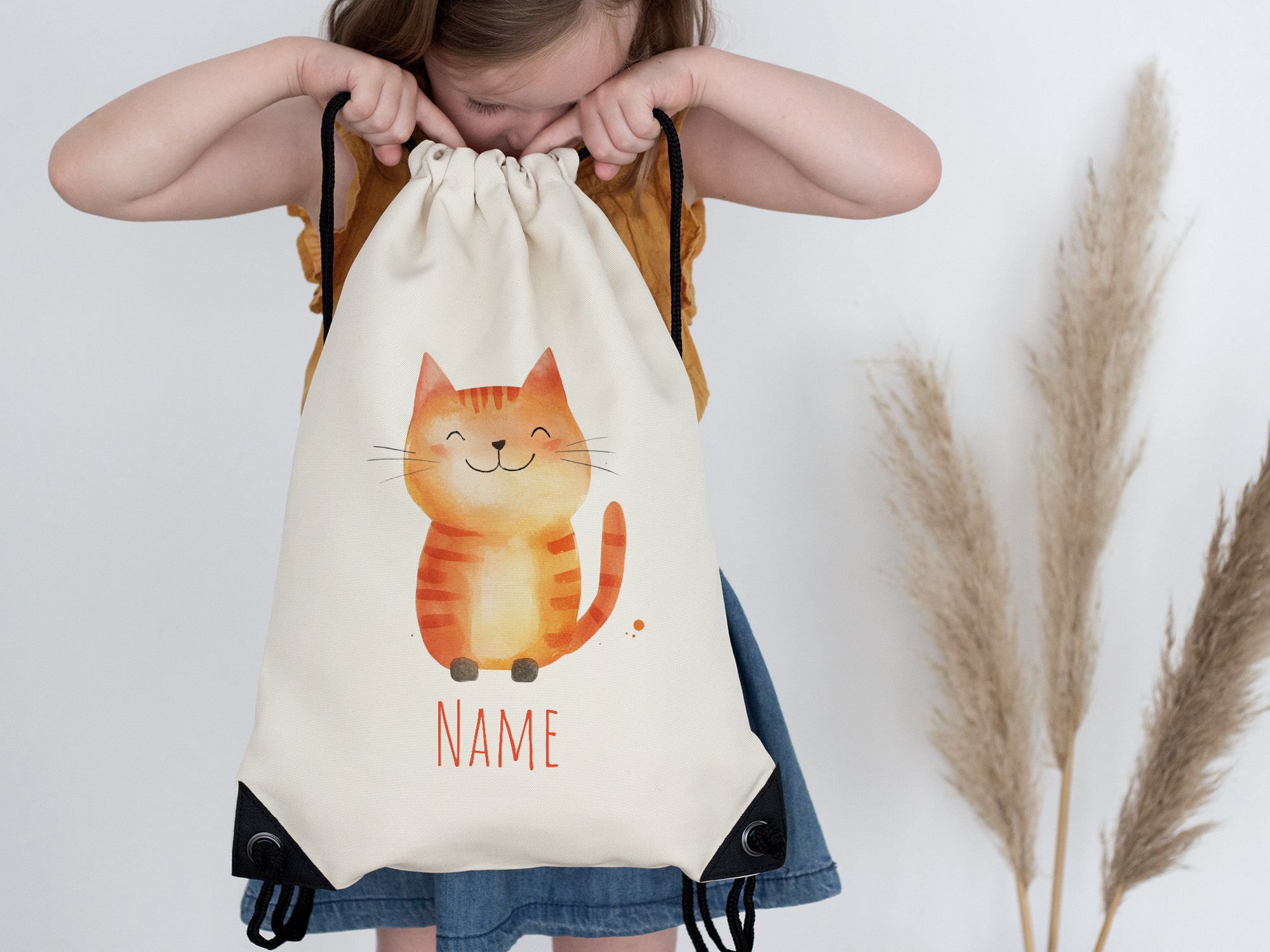 Beige Rucksack mit orangefarbener Katzenillustration und Platz für Namen.