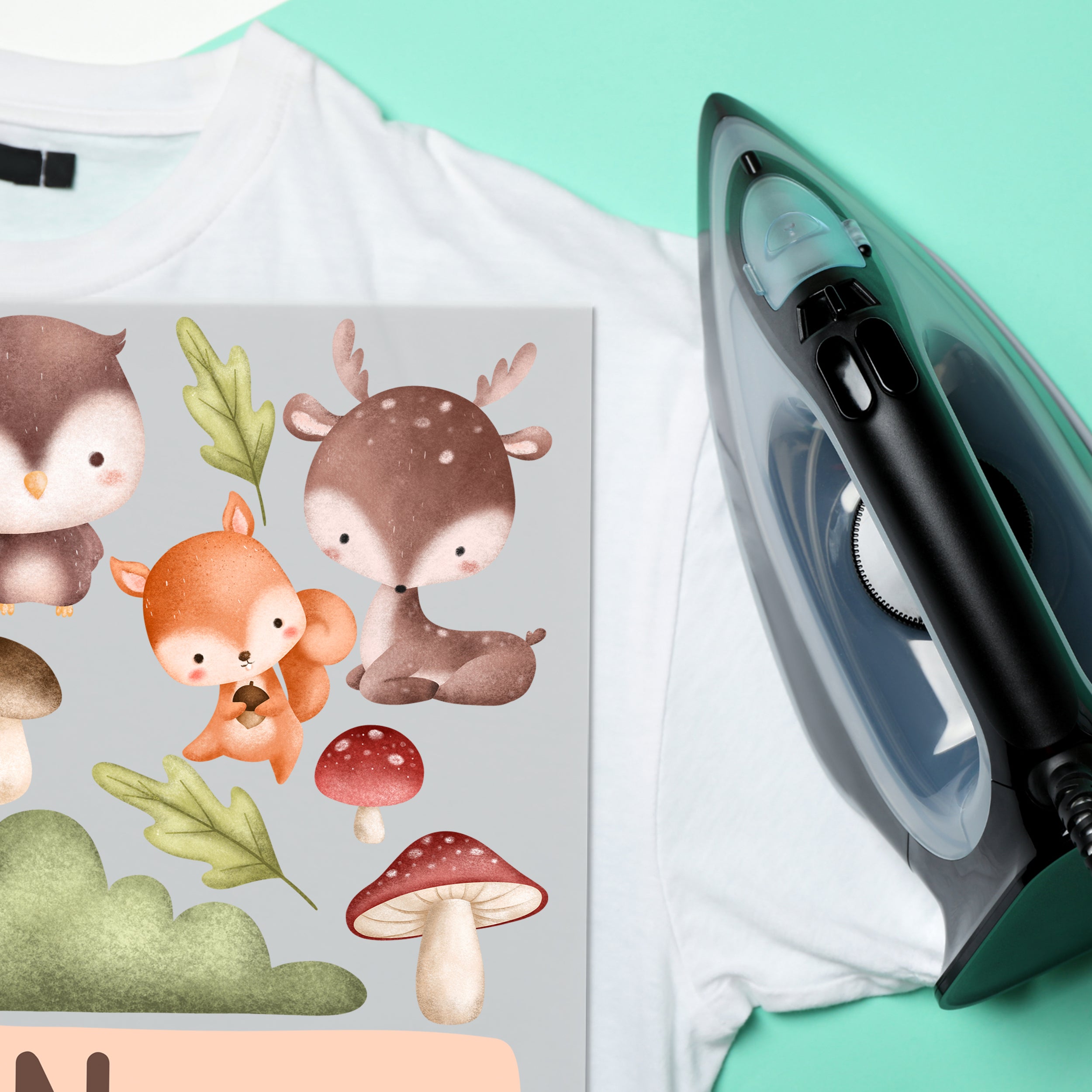 Weißes T-Shirt mit bunten Tiermotiven und Dampfbügeleisen.