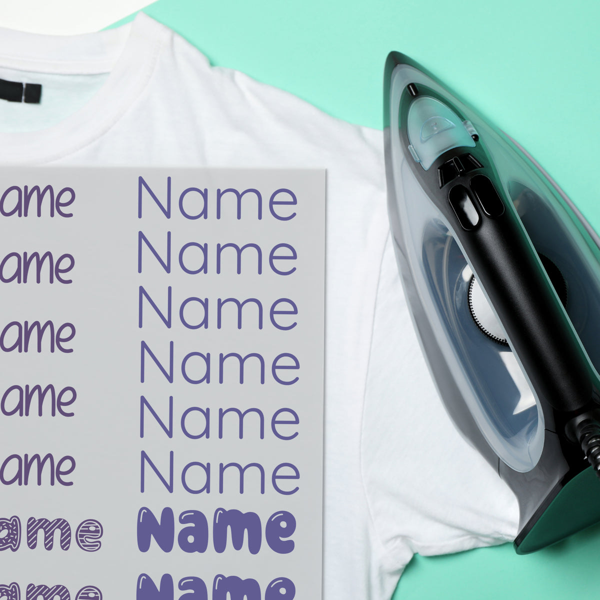 Weißes T-Shirt mit lila Namensaufklebern und Bügeleisen.