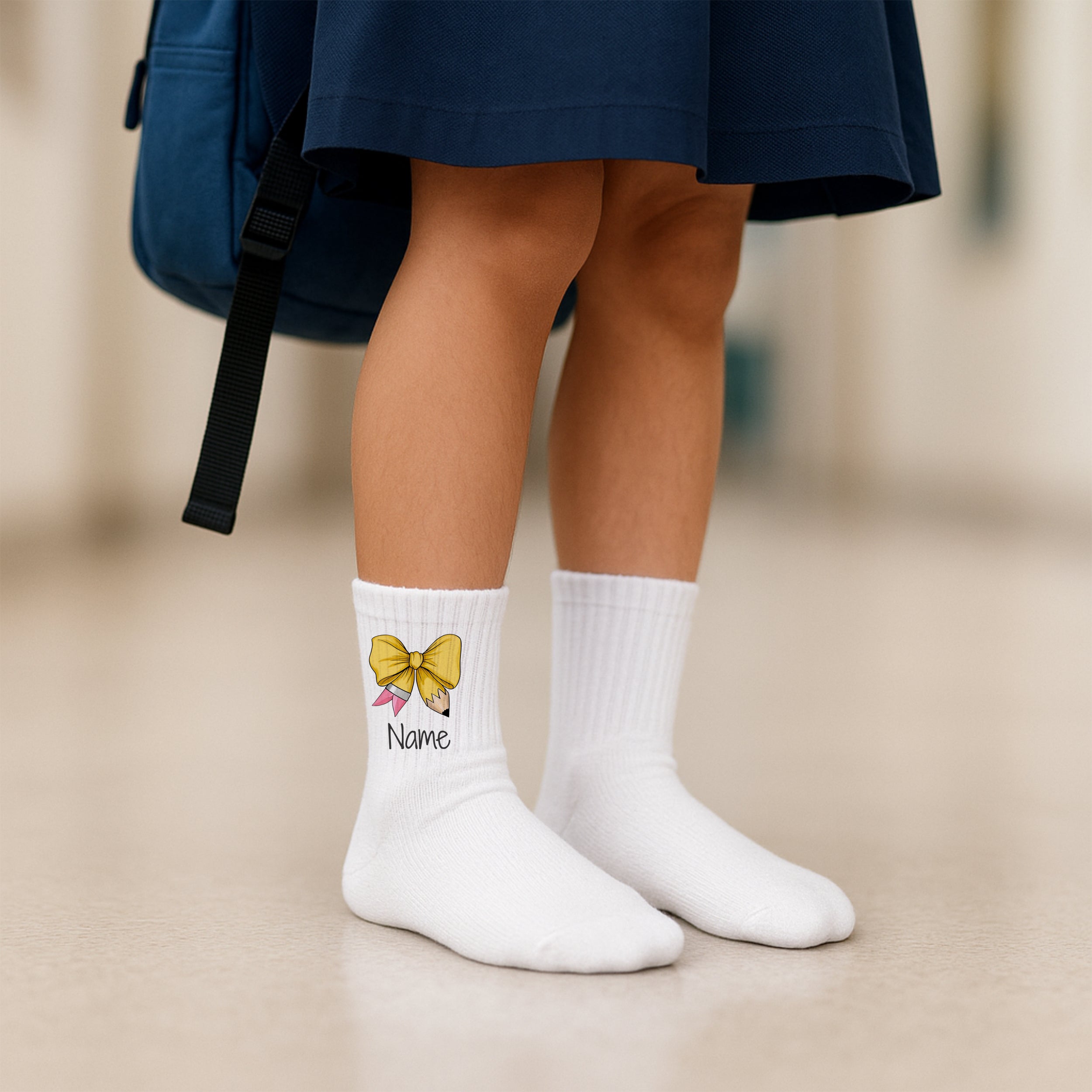 Weiße Socken mit gelber Schleife und personalisiertem Namen.