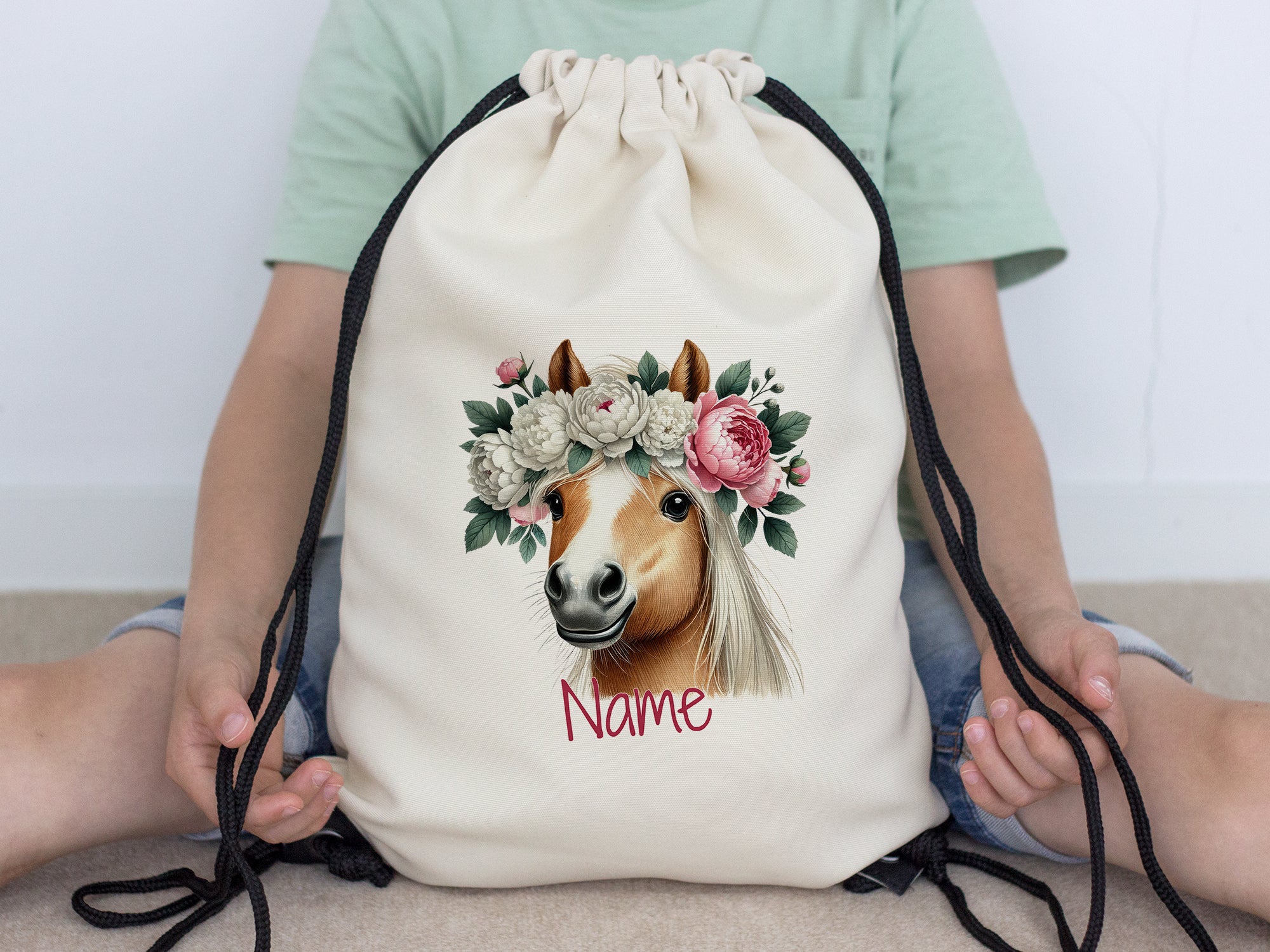 Beige Turnbeutel mit Pferdekopf und Blumenkranz.