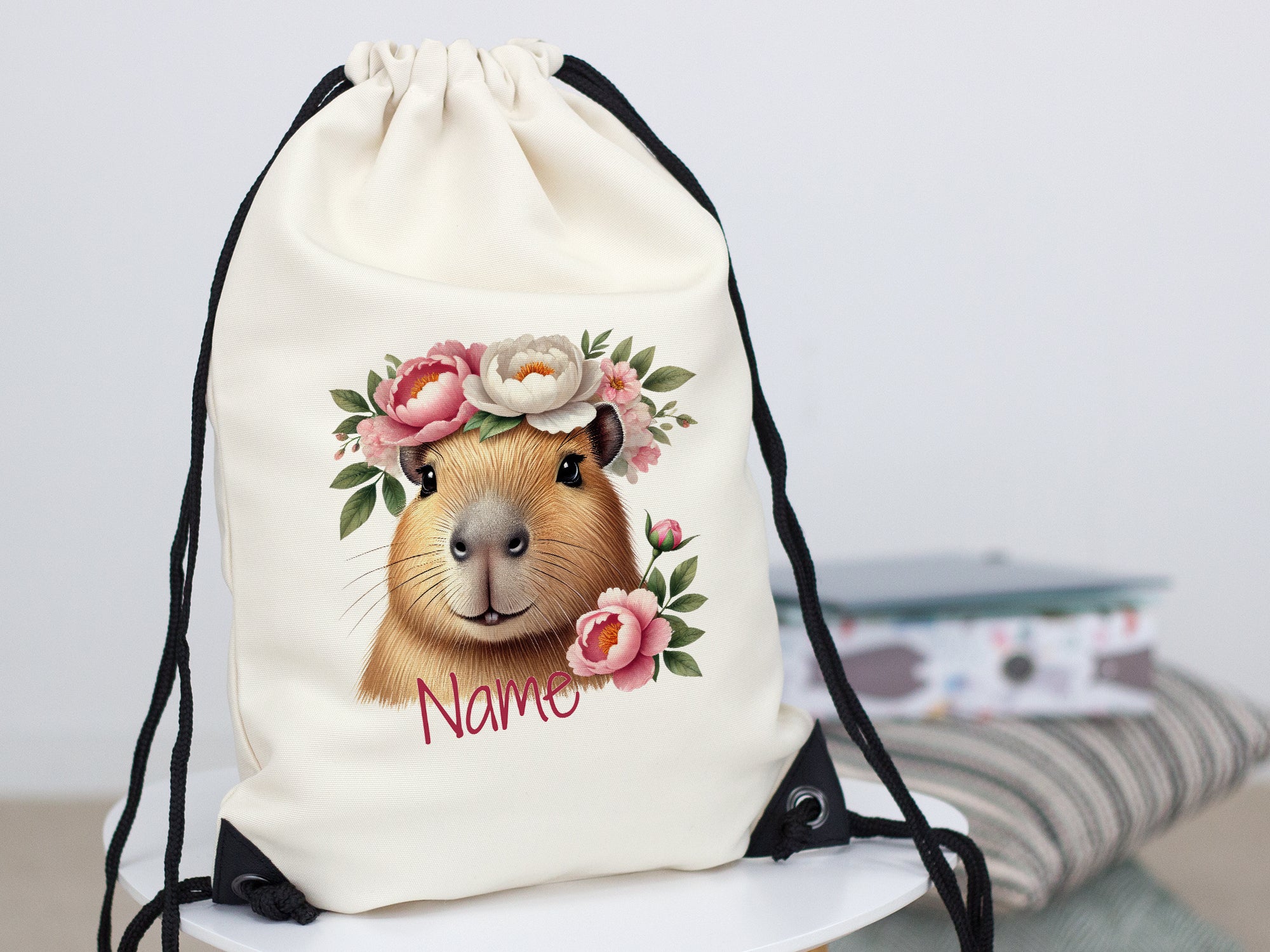 Beige Turnbeutel mit Capybara und Blumenmotiv.