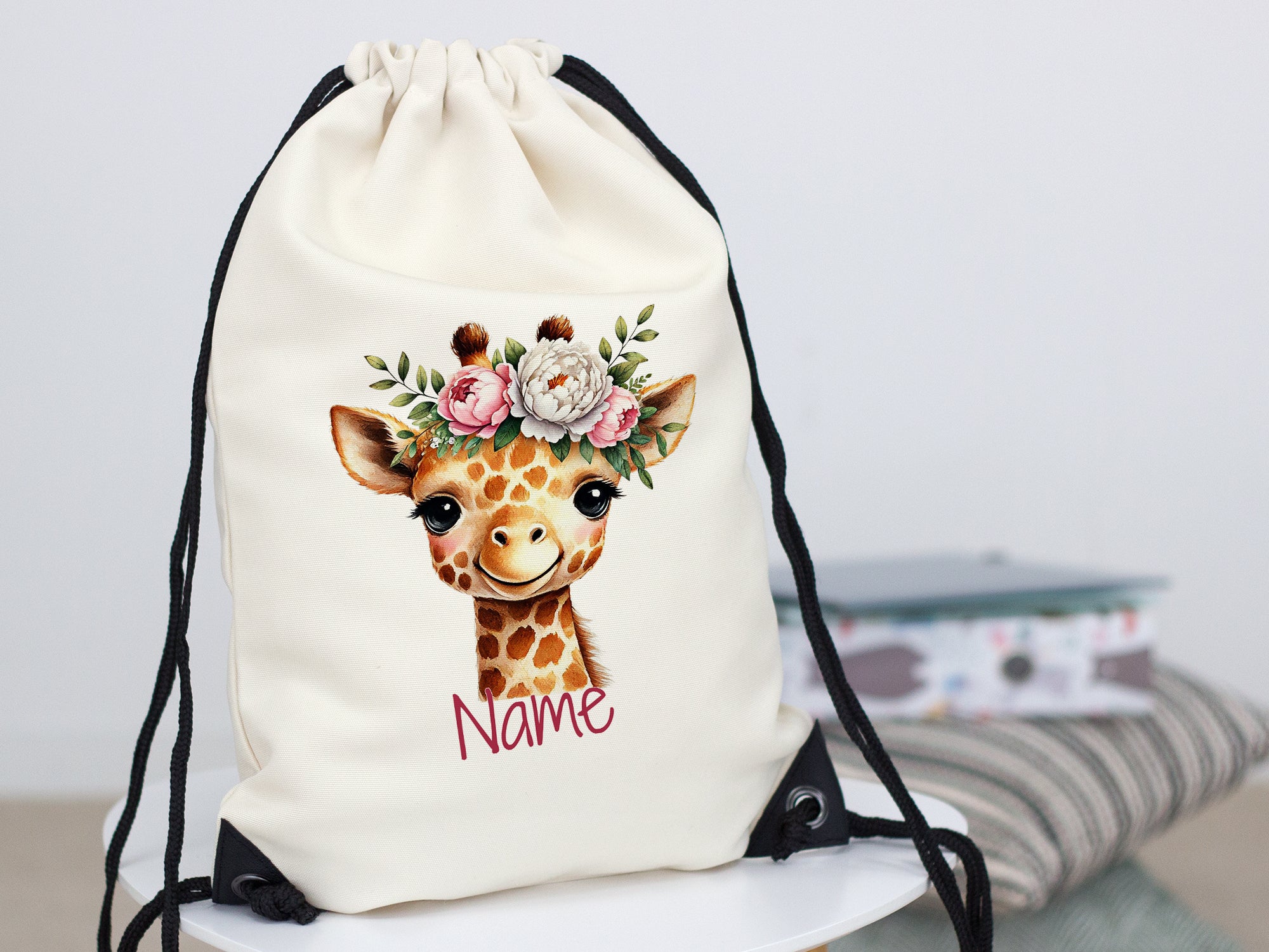 Beige Turnbeutel mit Giraffenmotiv und Blumenkranz.