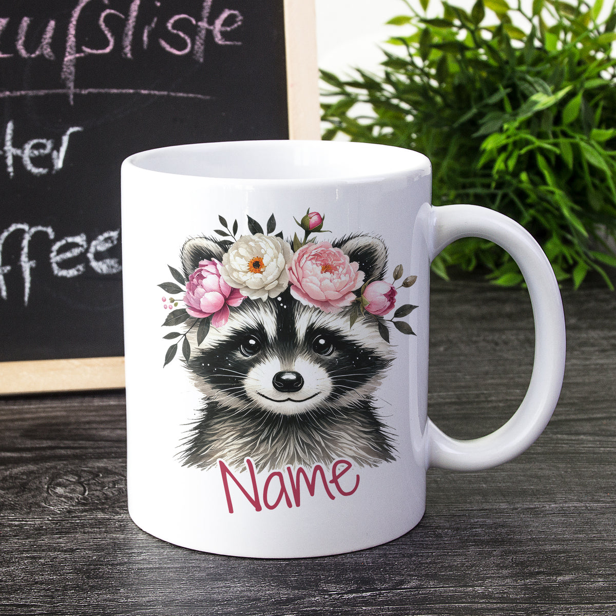 Weißer Kaffeebecher mit Waschbär und Blumenmotiv.