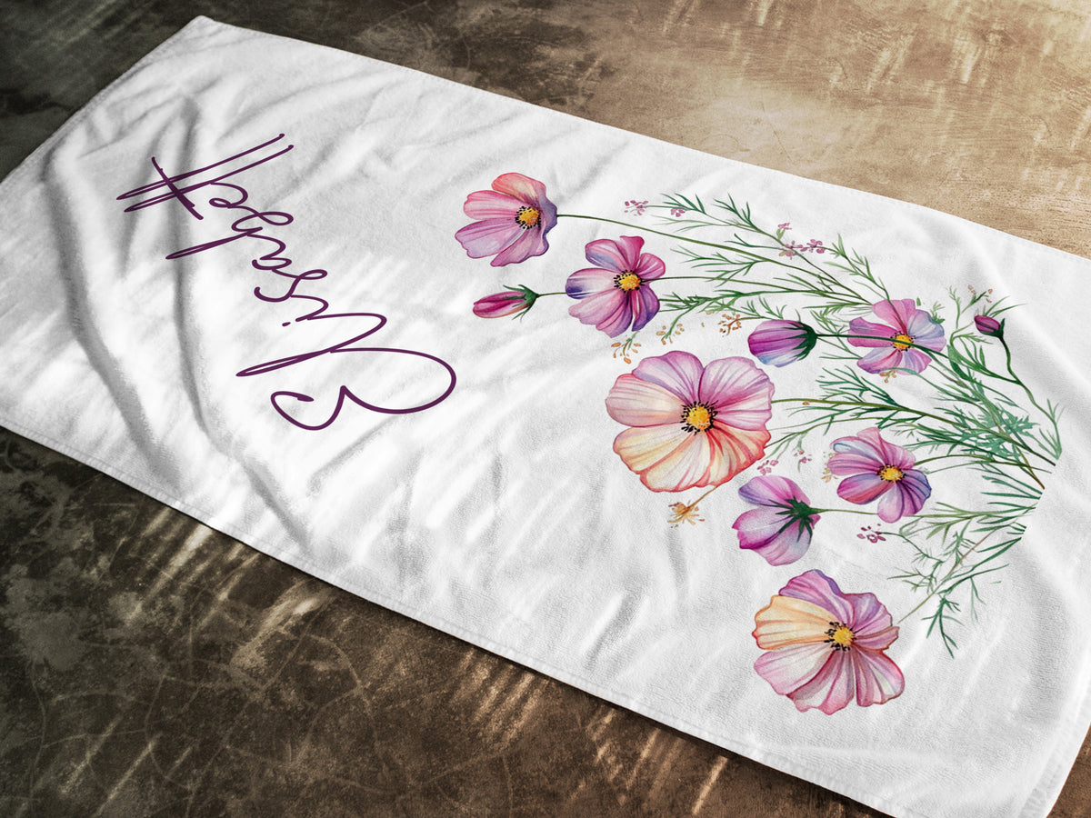 Weißes Handtuch mit bunten Blumen und Schriftzug.