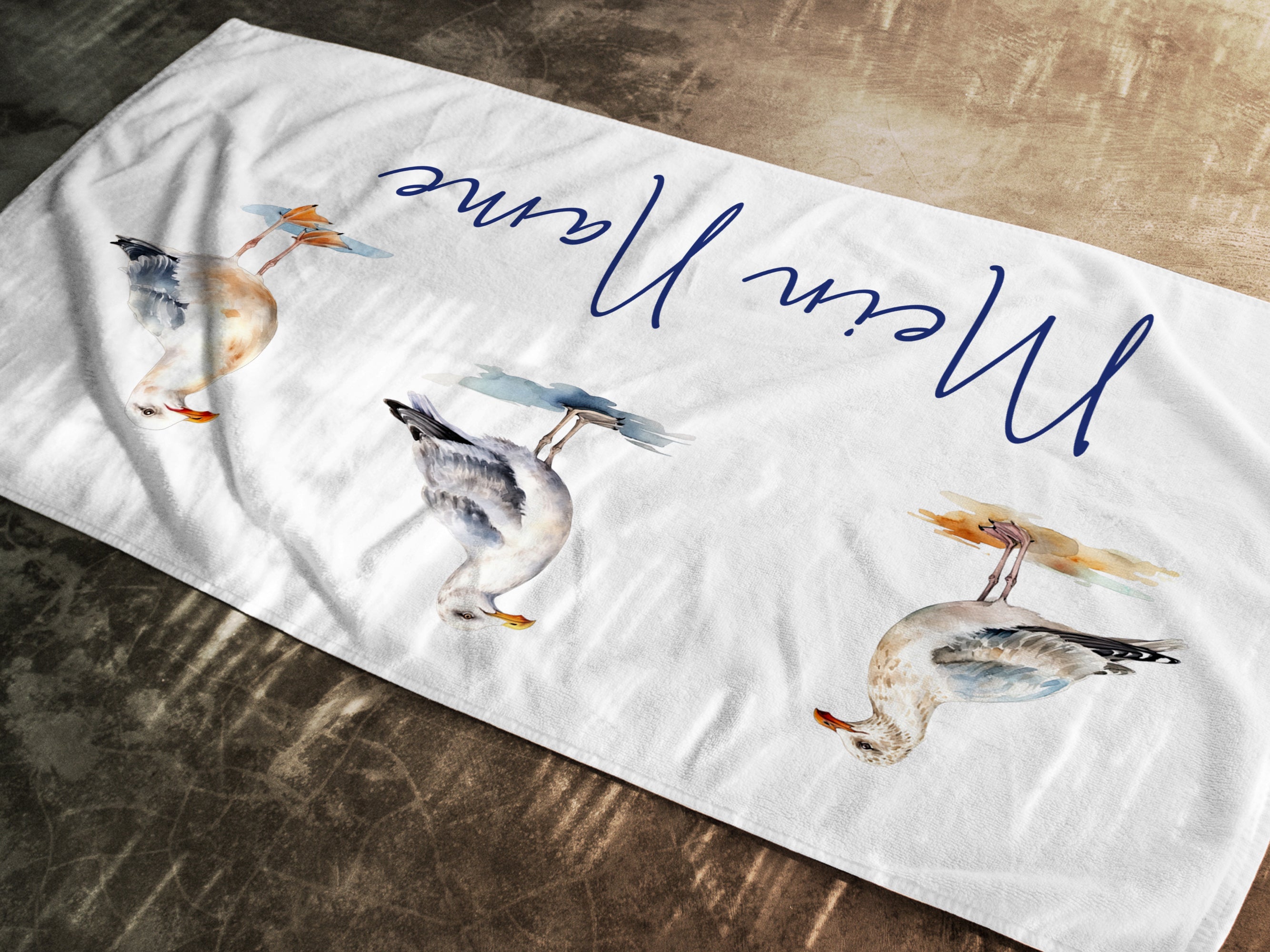 Weißes Handtuch mit bunten Entenmotiven und Schriftzug.