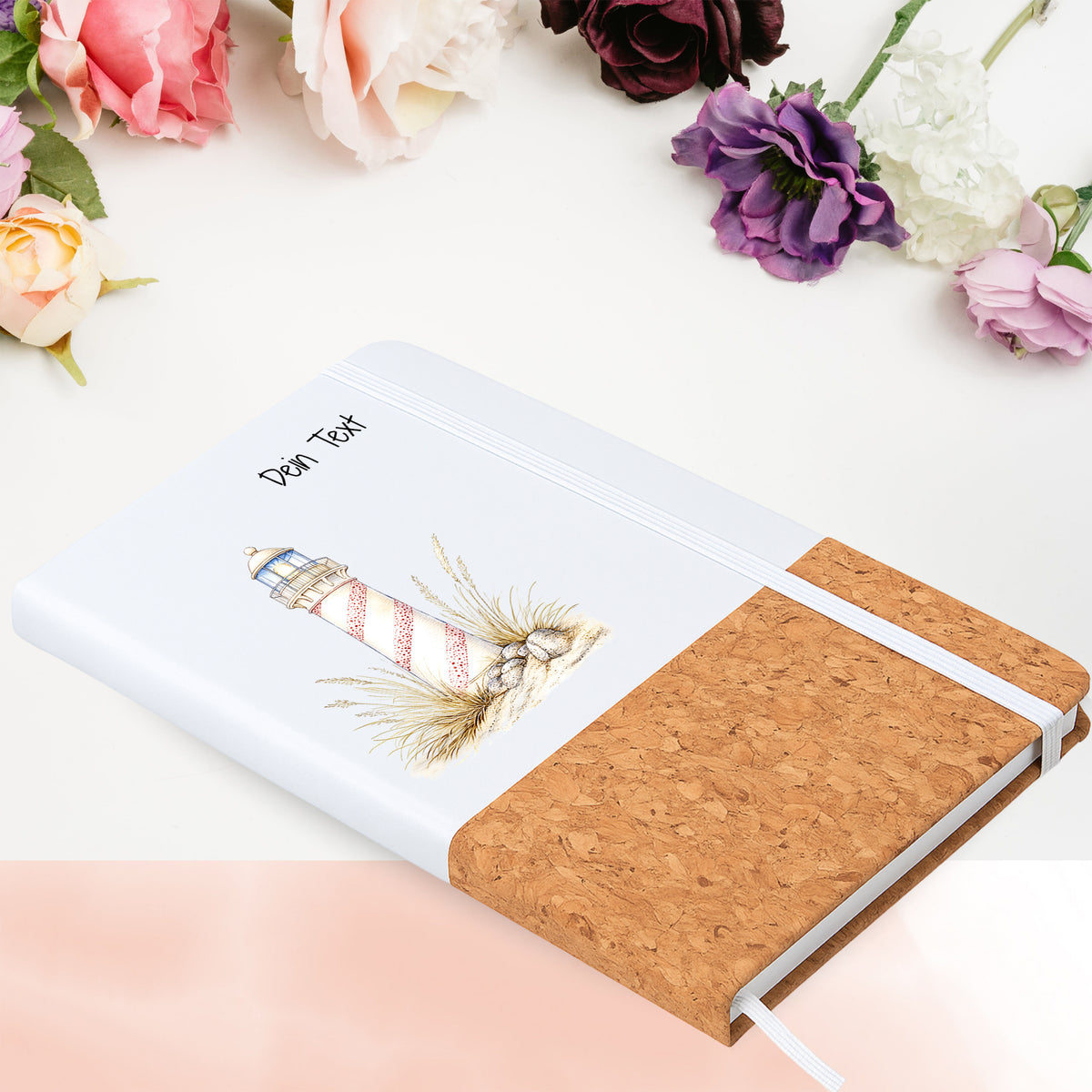 Notizbuch mit Leuchtturm im Dünengras in Blumenarrangement