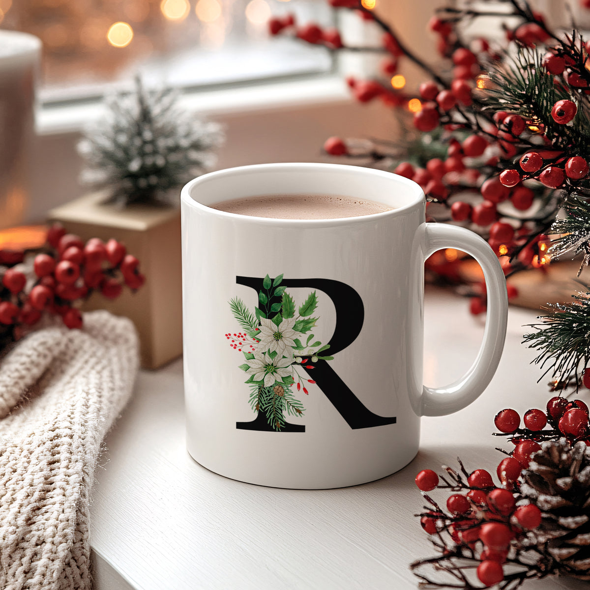 Weißer Becher mit floralem R-Motiv und heißem Getränk.