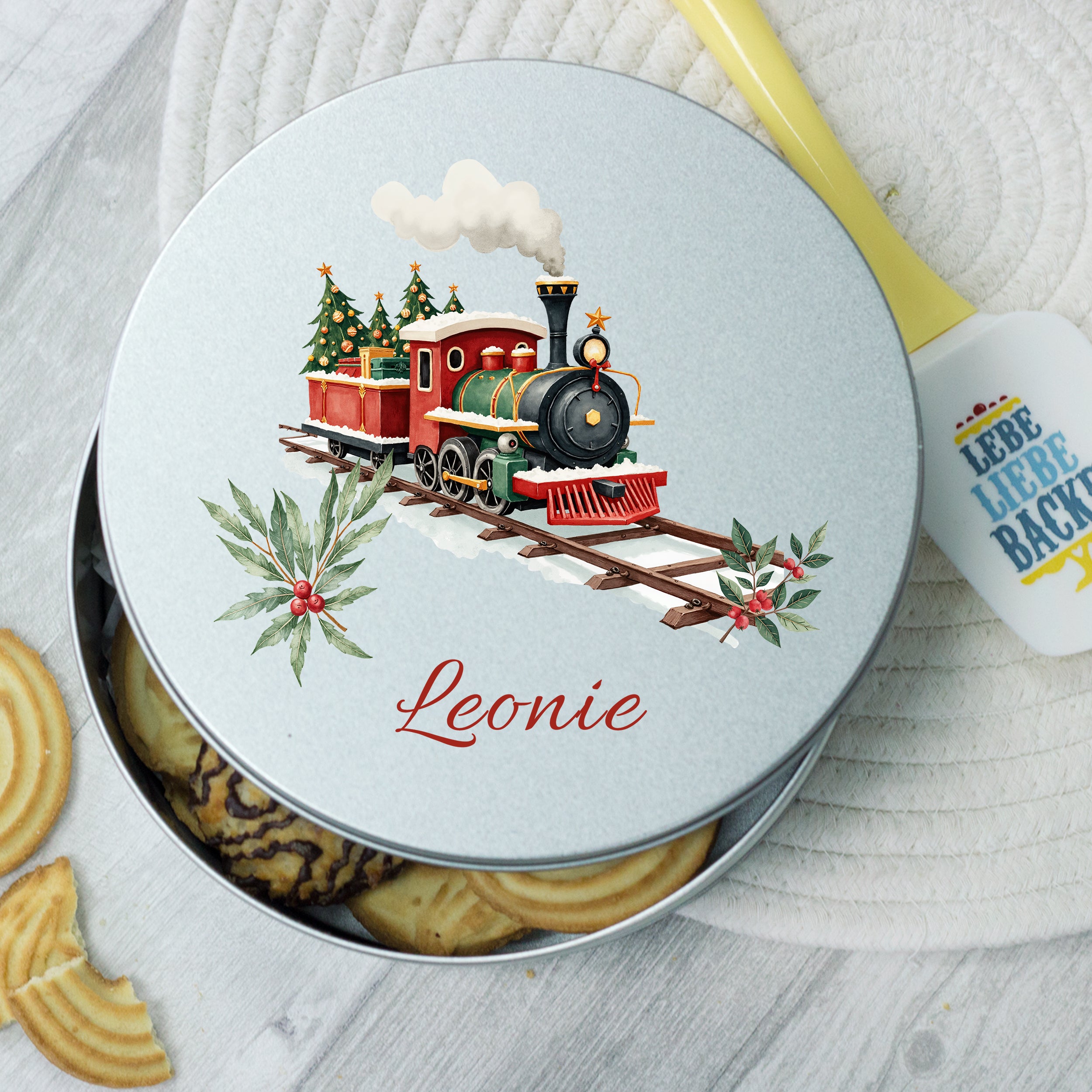 Runde, silberne Keksdose mit Lokomotive und Weihnachtsmotiven.