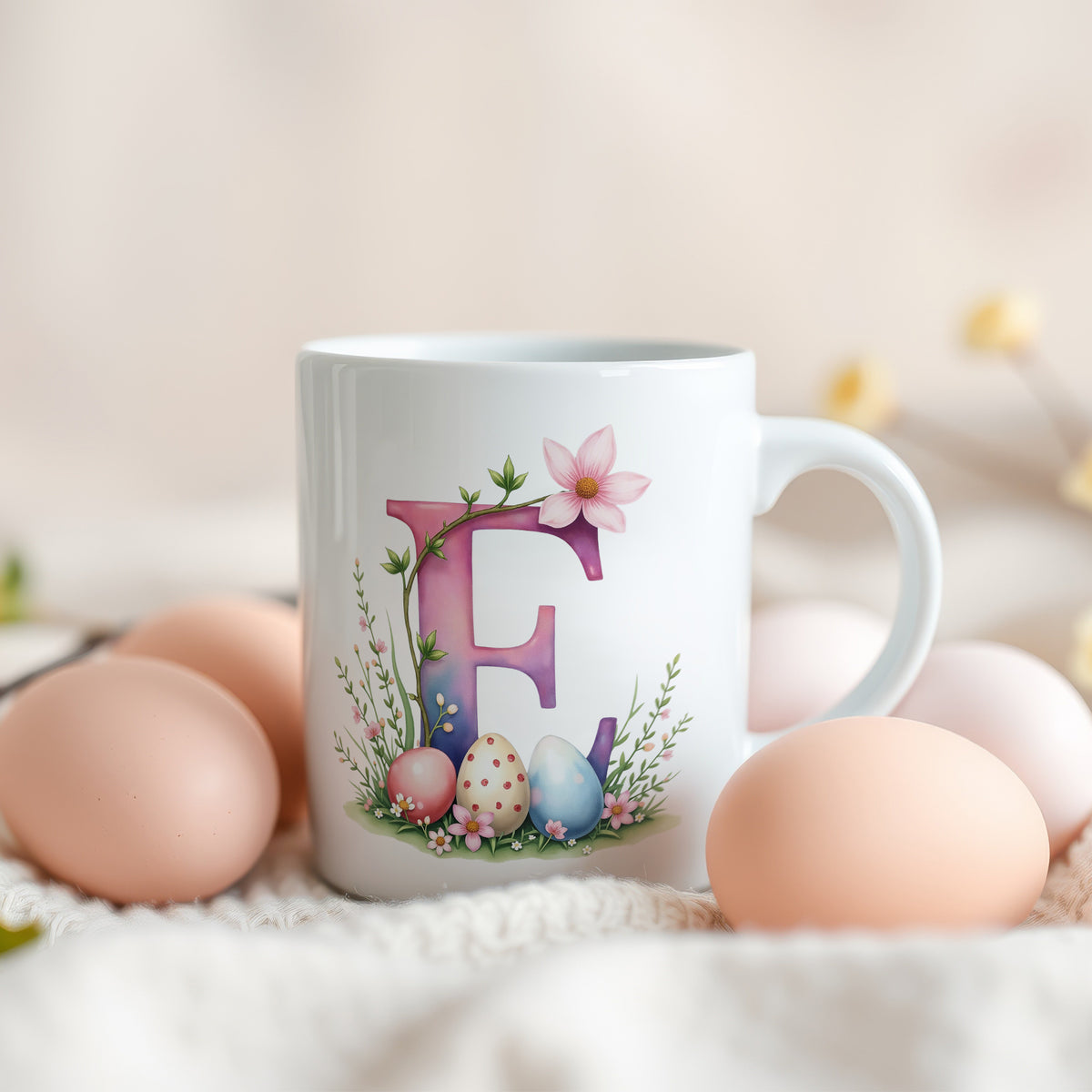 Weiße Tasse mit buntem Buchstaben E und Ostereiern.