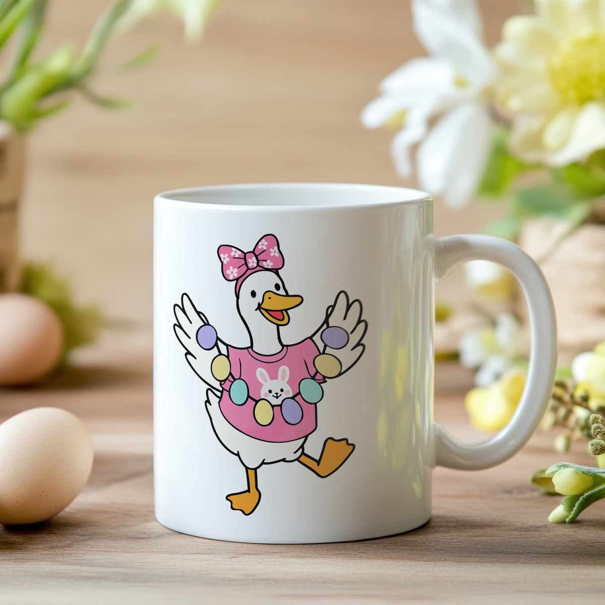 Tasse mit bunter Ente, rosa Schleife und Ostereiern.