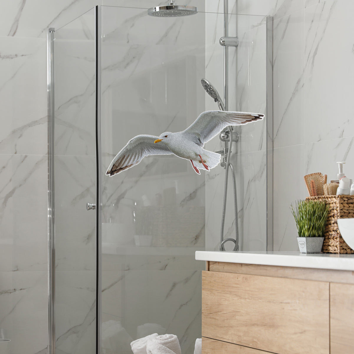 Graue Möwe fliegt vor gläserner Duschwand im Badezimmer.