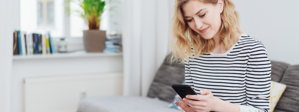 Frau mit gestreiftem Shirt, Smartphone in der Hand, gemütliche Atmosphäre.