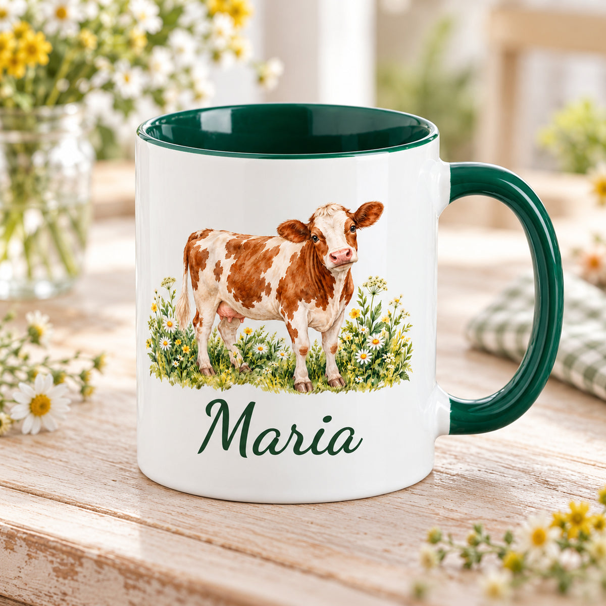 Kuh-Tasse mit braun-weißer Kuh zwischen Wildblumen und Wunschname in Schrägansicht mit sichtbarem dunkelgrünem Innenraum