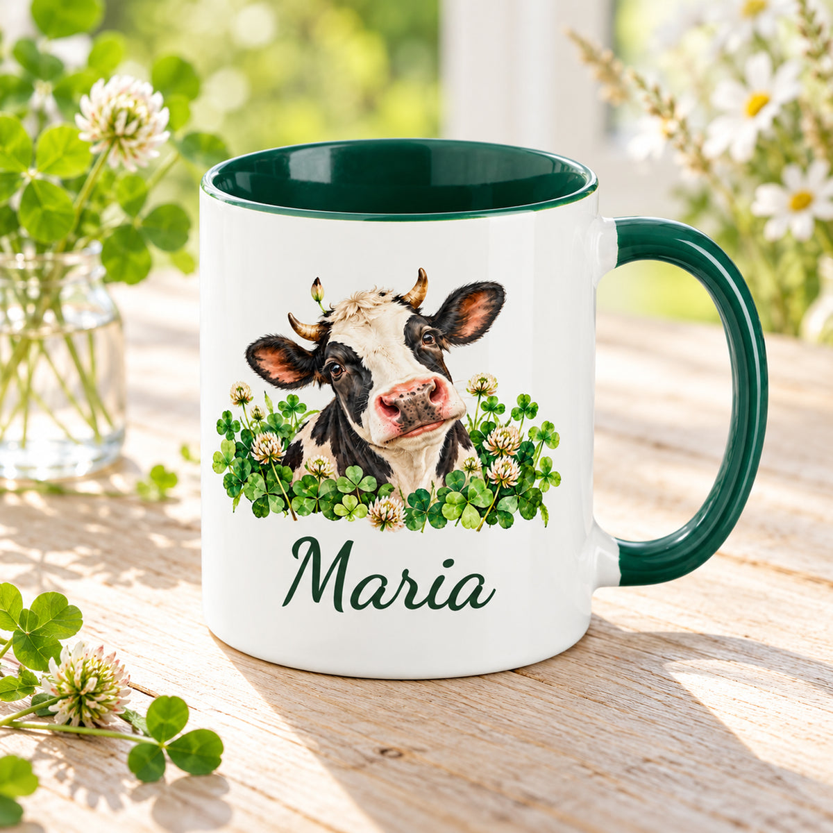 Kuh-Tasse mit schwarz-weißer Kuh zwischen Kleeblättern und Blüten und Wunschname in Schrägansicht mit sichtbarem dunkelgrünem Innenraum