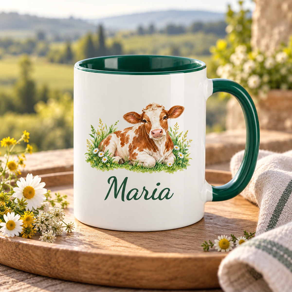 Kuh-Tasse mit ruhender braun-weißer Kuh mit Gänseblümchen und Wunschname auf einem Holztablett mit Stoffserviette und Wiesenblumen