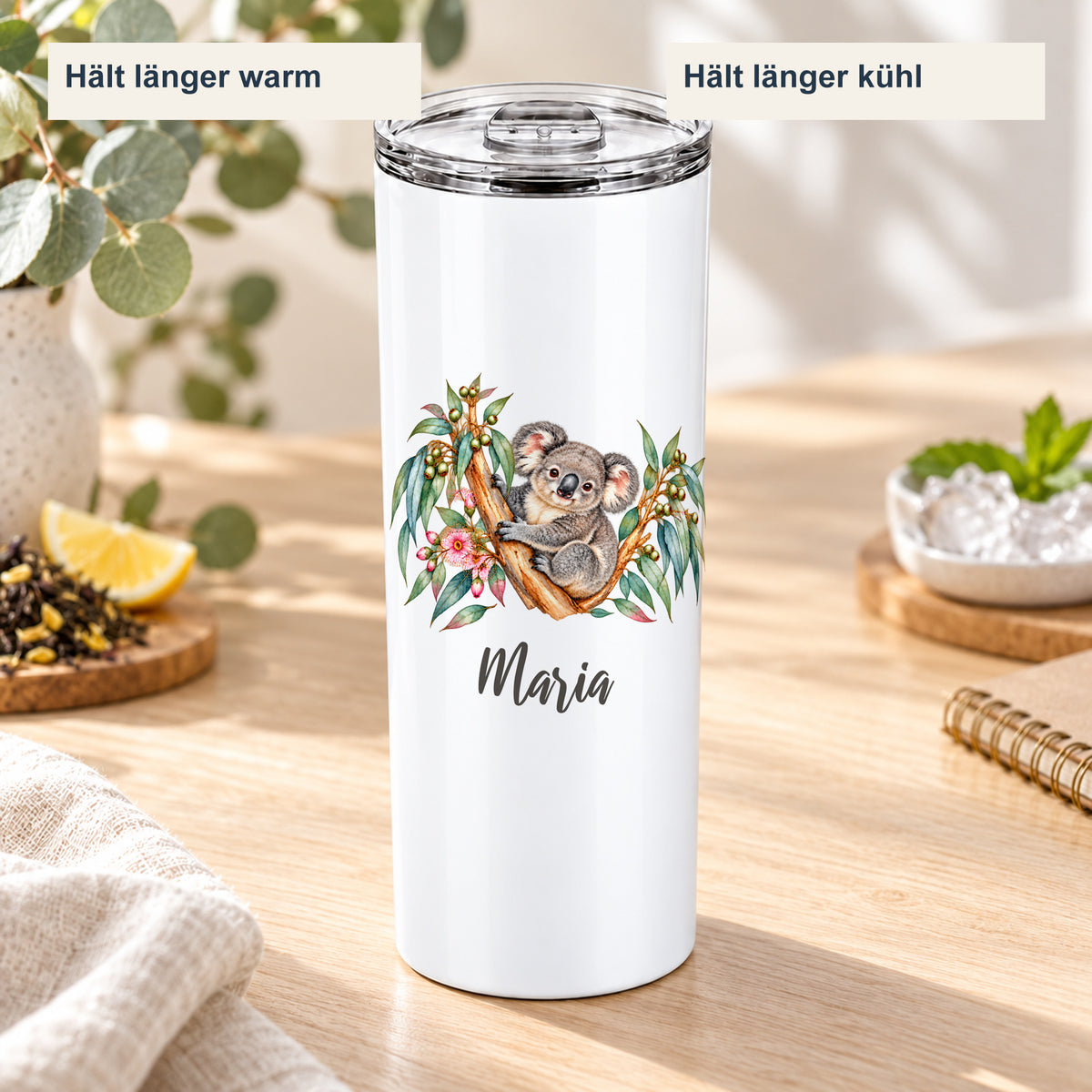 Thermobecher mit Koala-Motiv in einer sommerlichen Getränkeszene mit Hinweisen auf länger warme und länger kühle Getränke.