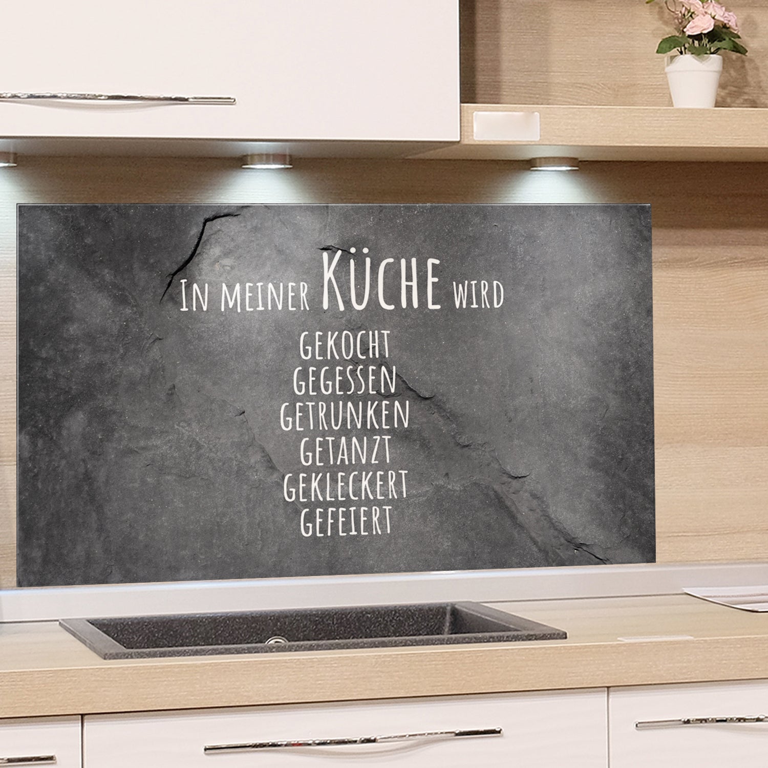 Schwarze Küchenrückwand mit weißem Schriftzug und Sprüchen.