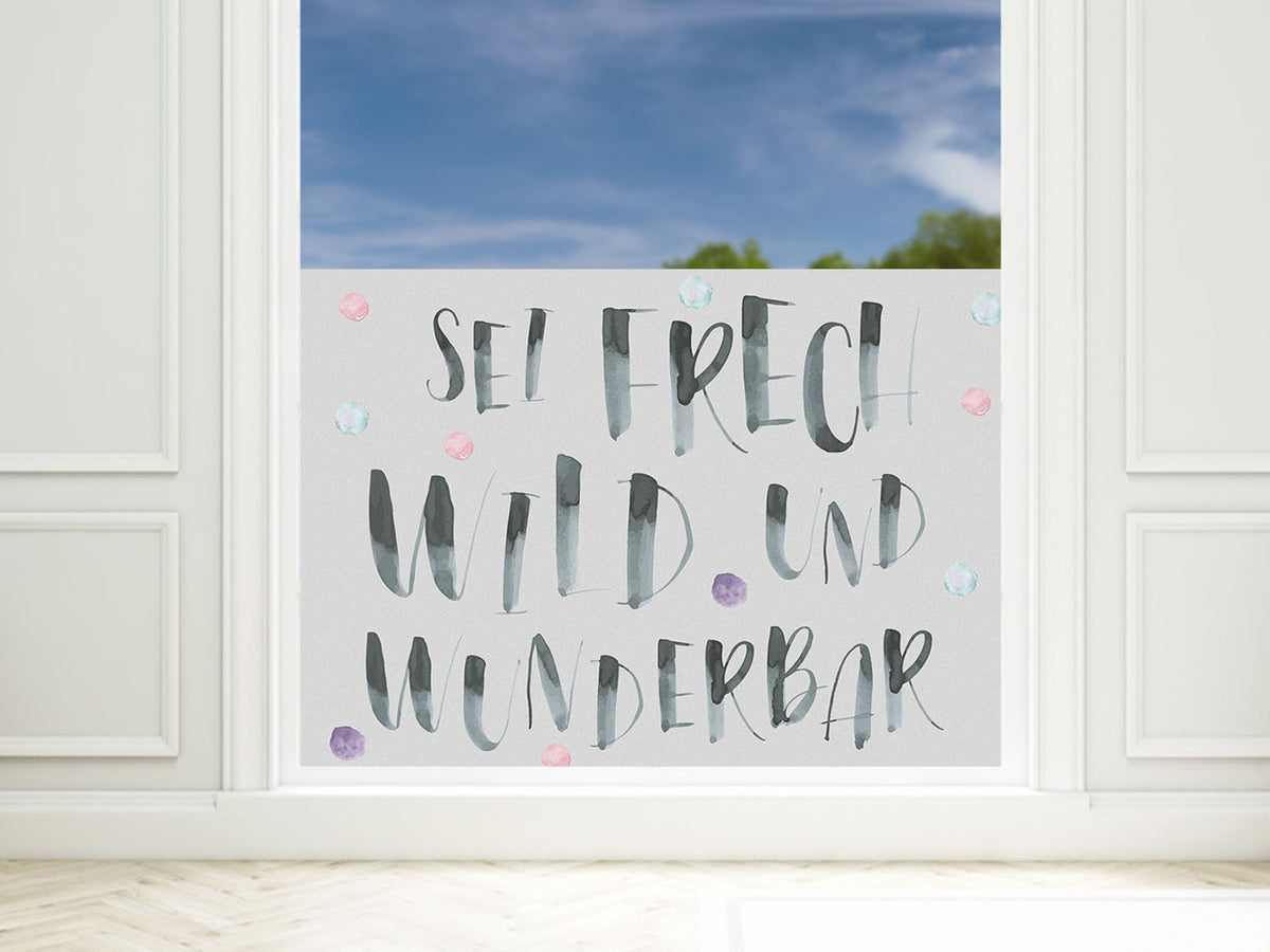 Wanddeko mit handgeschriebenem Spruch in Grau und Pastellfarben.