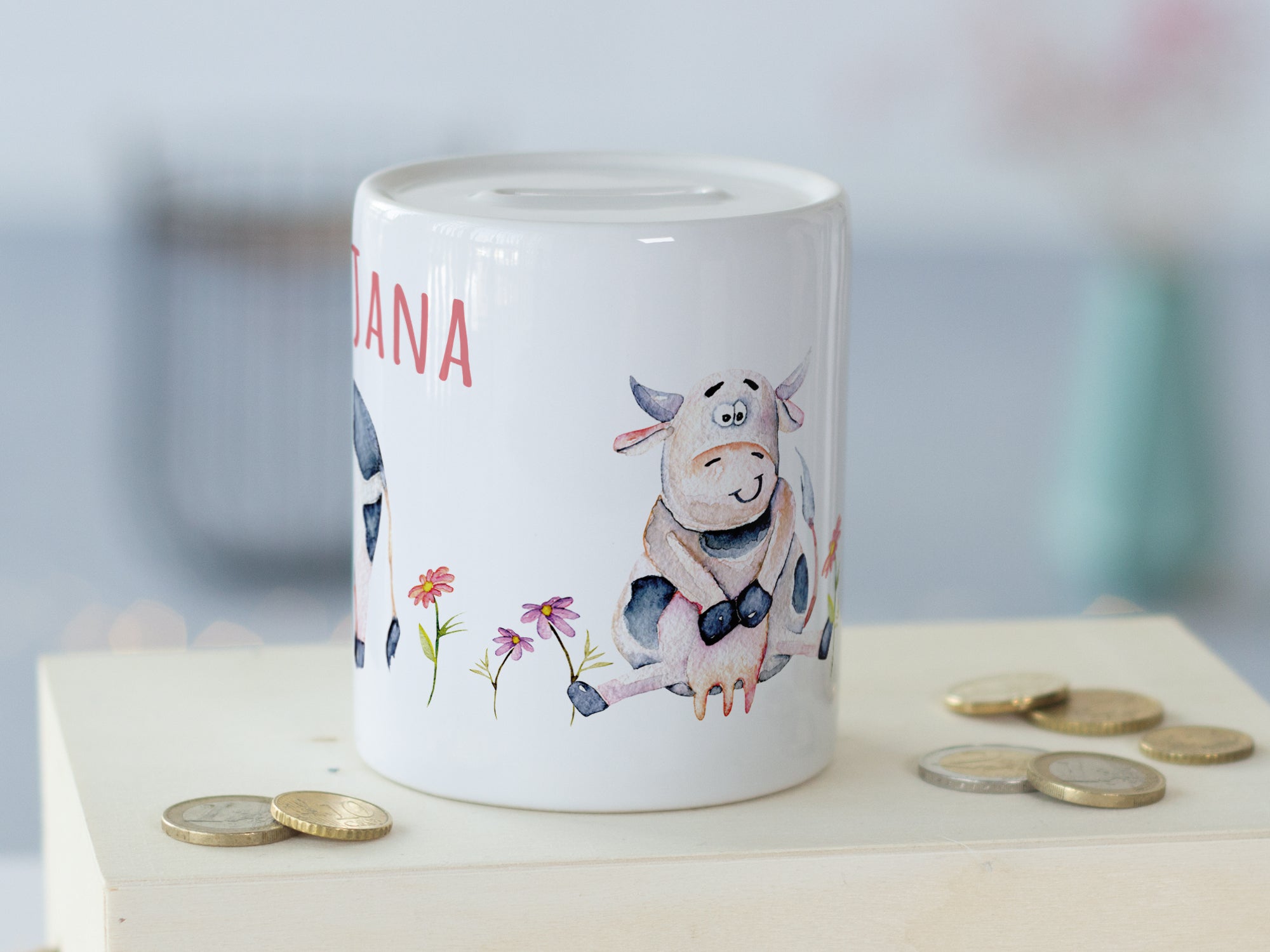 Sparschwein mit Kuhmotiven und bunten Blumen.