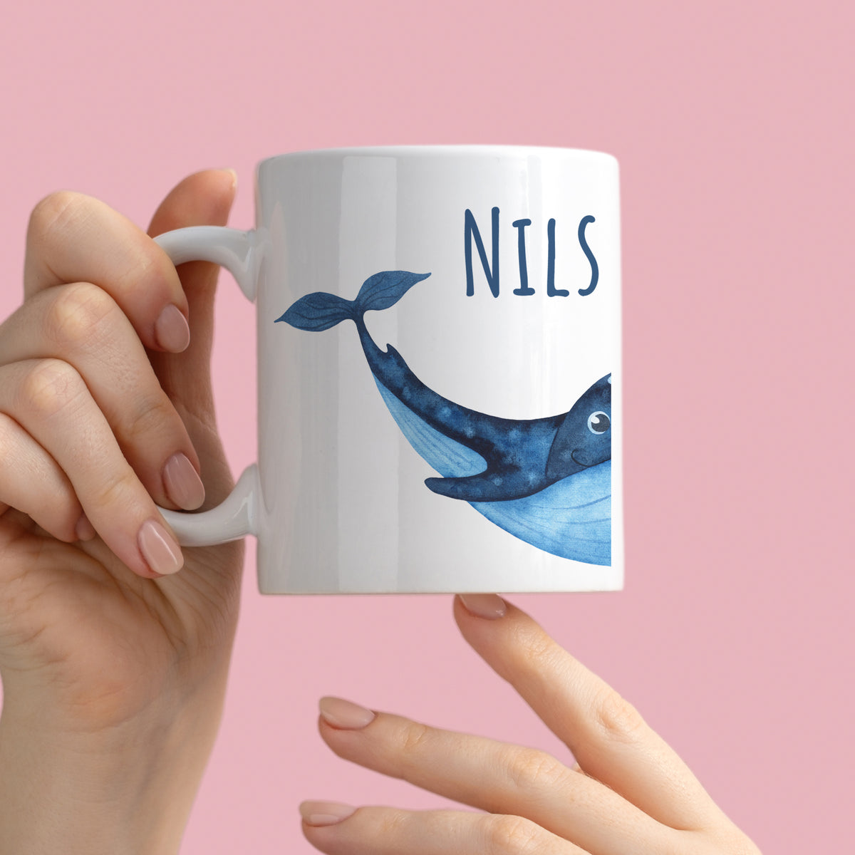 Weißer Becher mit blauer Wal-Illustration und Namen "NILS".
