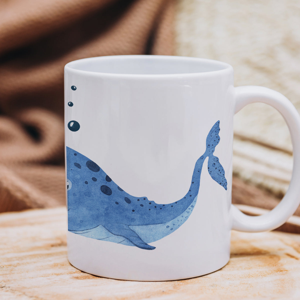 Weißer Becher mit blauem Wal-Motiv und Luftblasen.