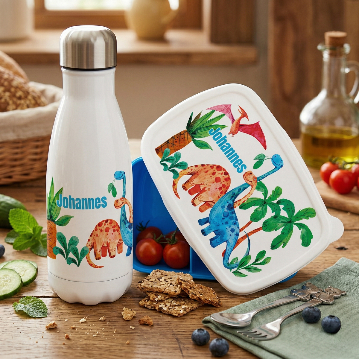 Weißer Edelstahl-Trinkflasche und bunte Brotdose mit Dinosauriern.