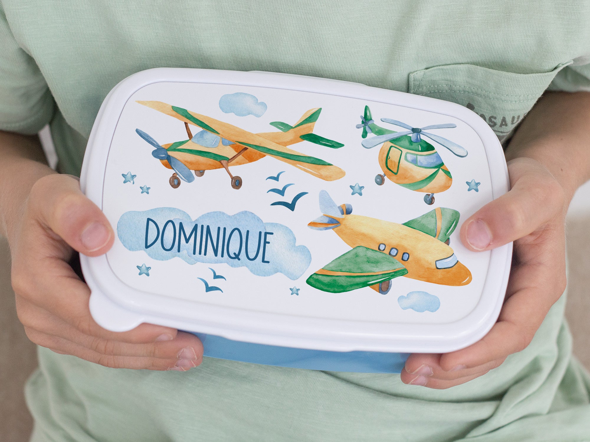 Bunte Brotdose mit Flugzeugen und dem Namen Dominique.