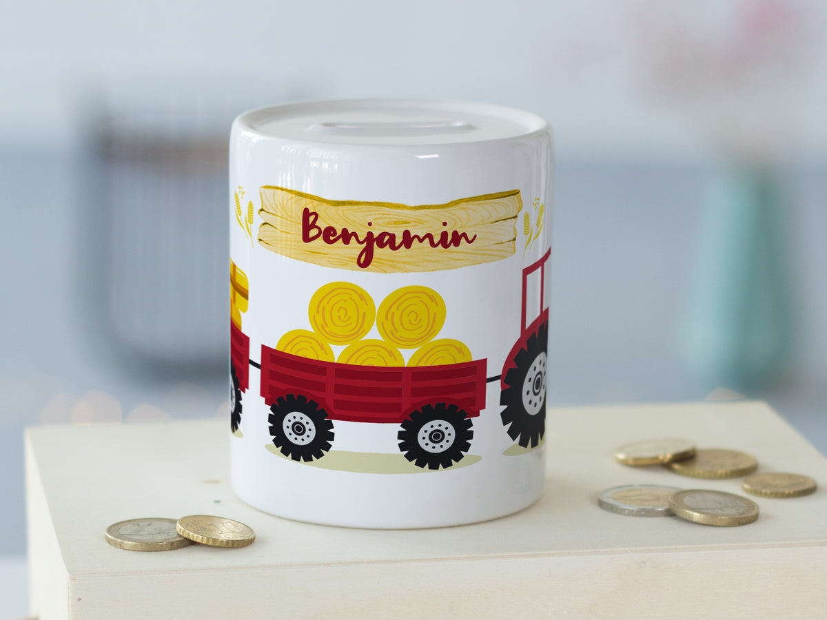 Spardose mit rotem Traktor und gelben Heuballen.
