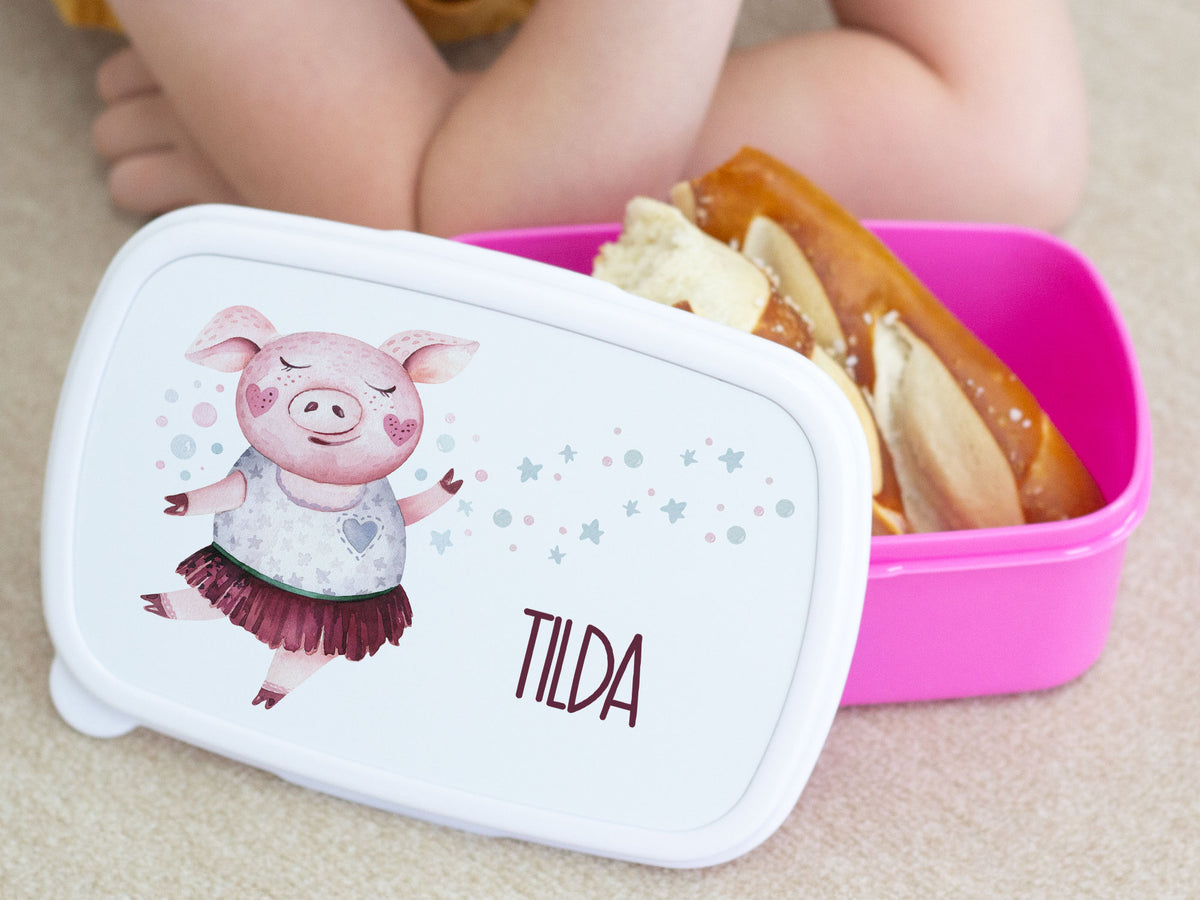 Rosa Brotdose mit tanzendem Schwein und Aufschrift "TILDA".