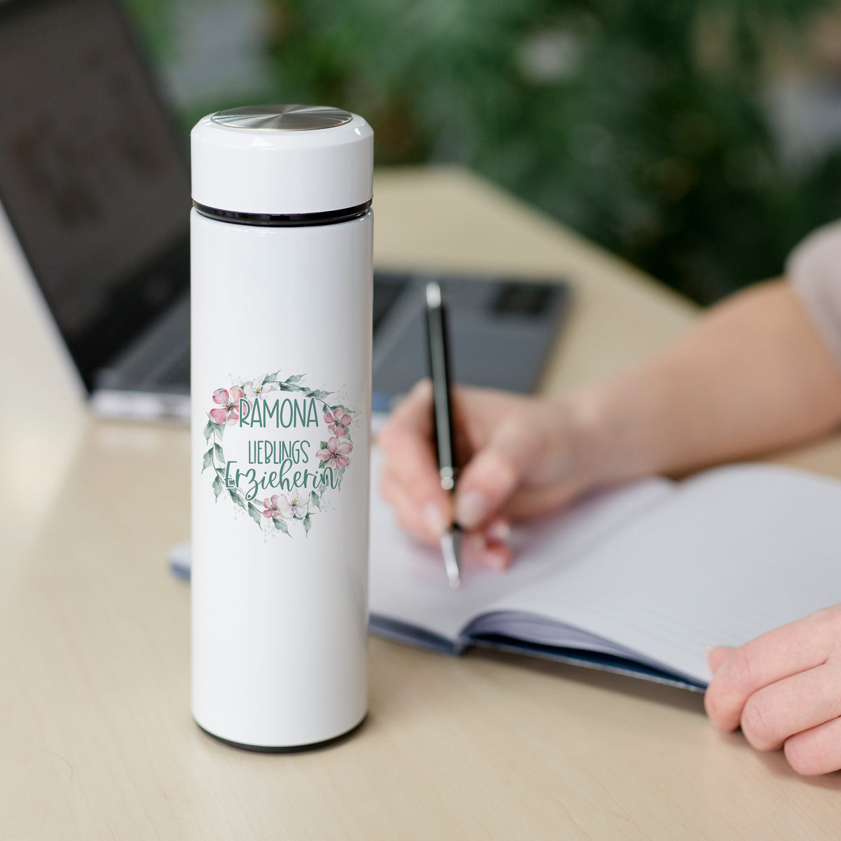 Weiße Thermosflasche mit floralem Design und Namen.