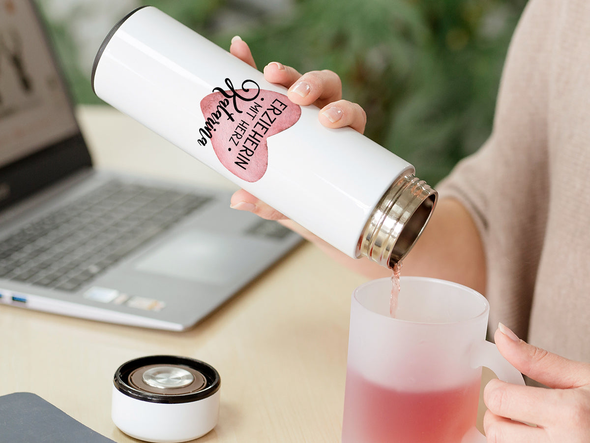 Weißer Thermobecher mit pinkem Aufdruck, Tee wird eingeschenkt.